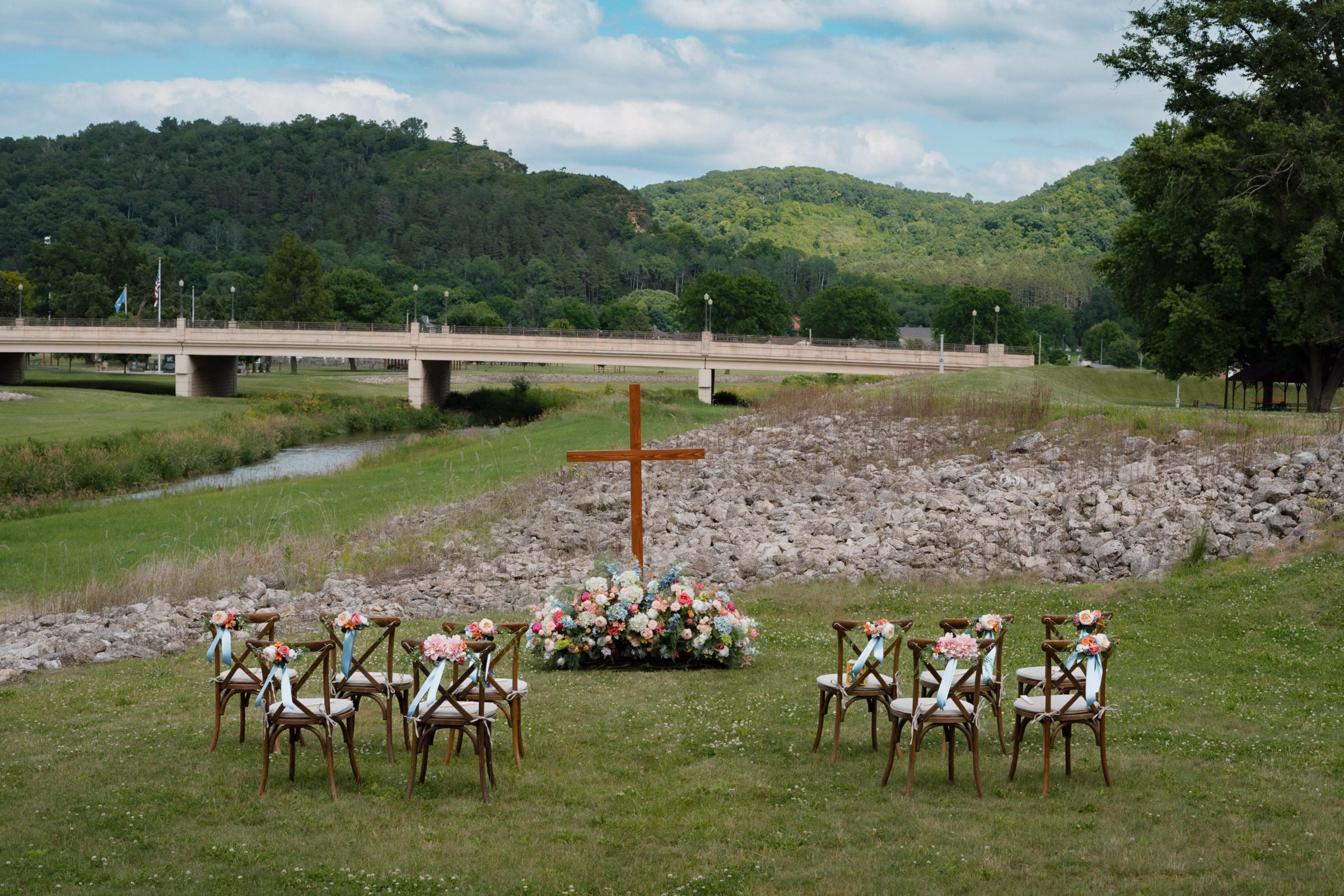 Outdoor wedding ceremony seating and floral arch along the creek at The Mill on Rush Creek in Rushford, Minnesota