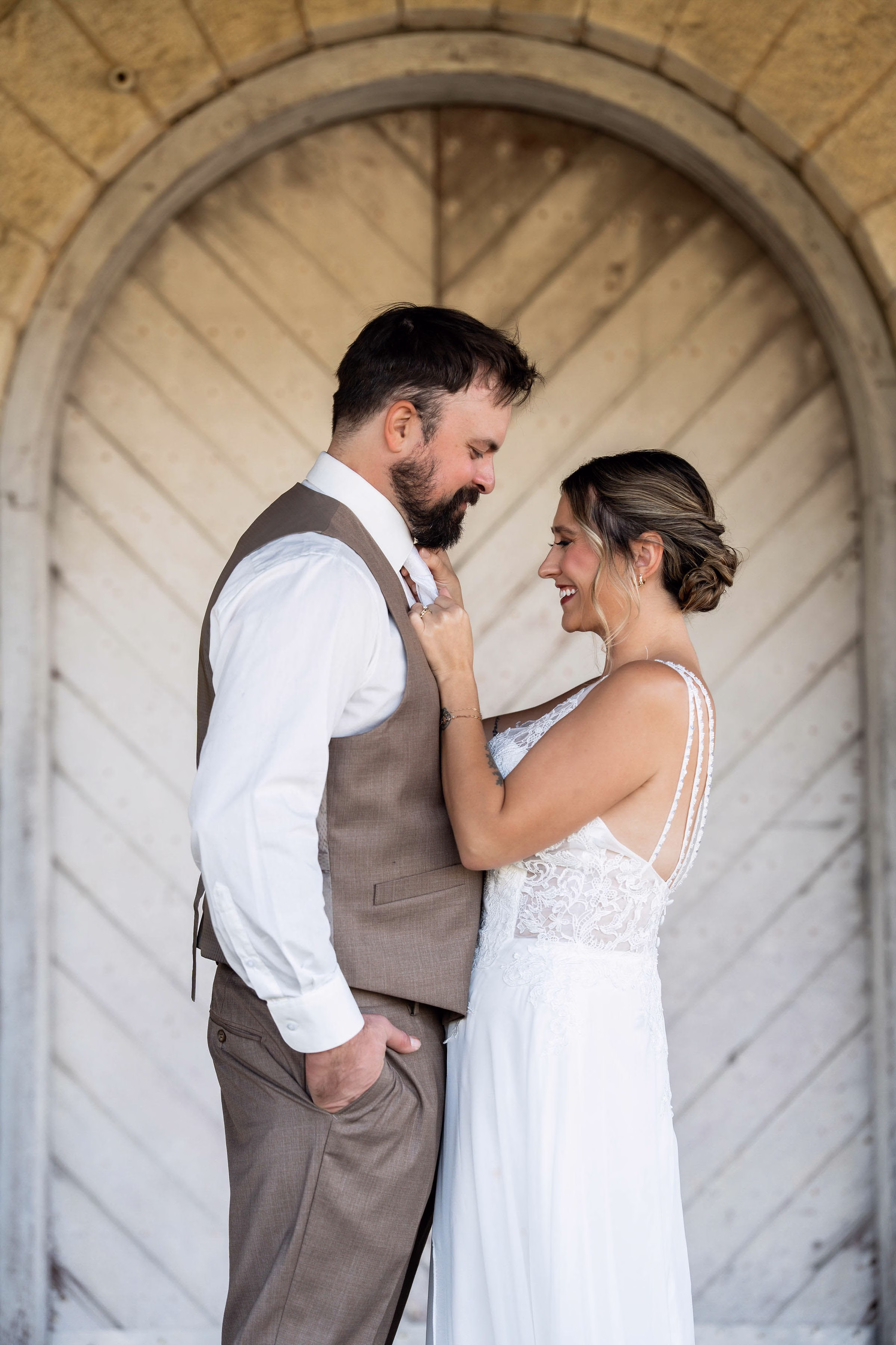 Bride and groom sharing a close moment under a stone archway at The Mill on Rush Creek