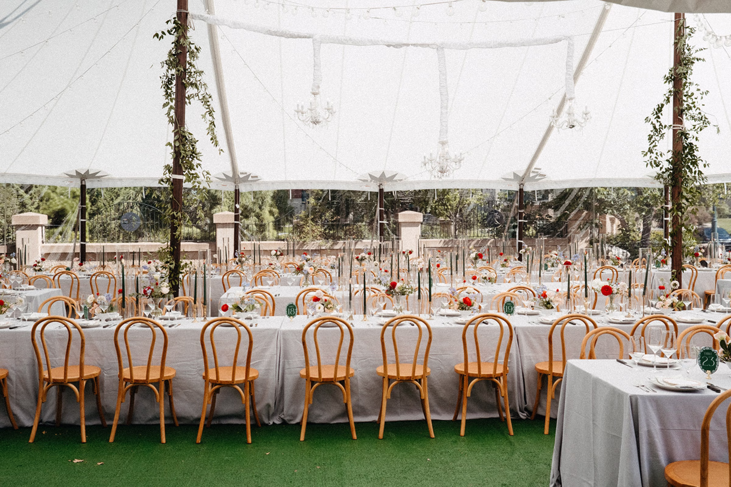 long reception tables set under outdoor tent, making for a French garden wedding atmosphere