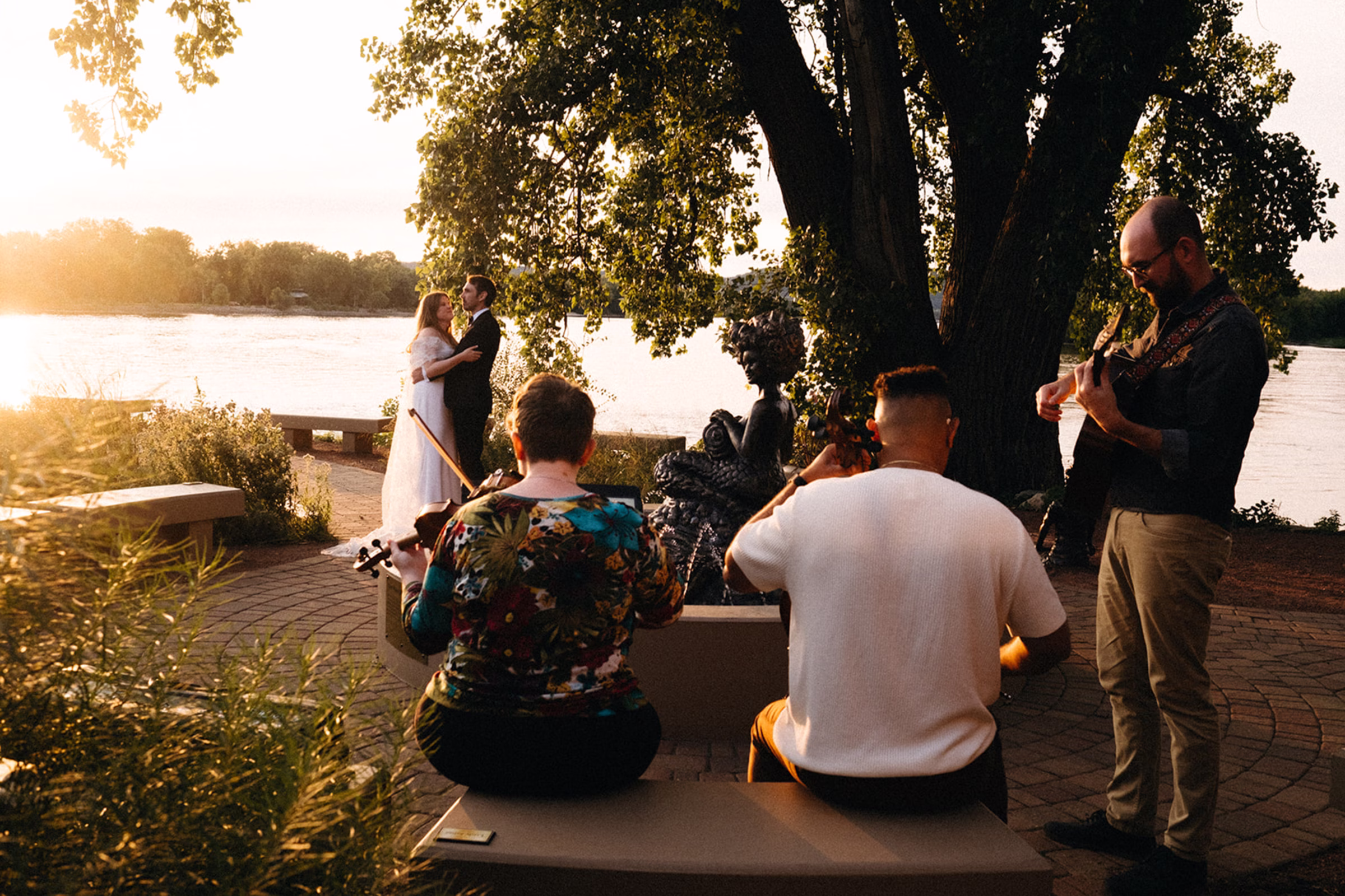 the couple shares a sunset dance on the patio by the water, with music from Freegrass Trio