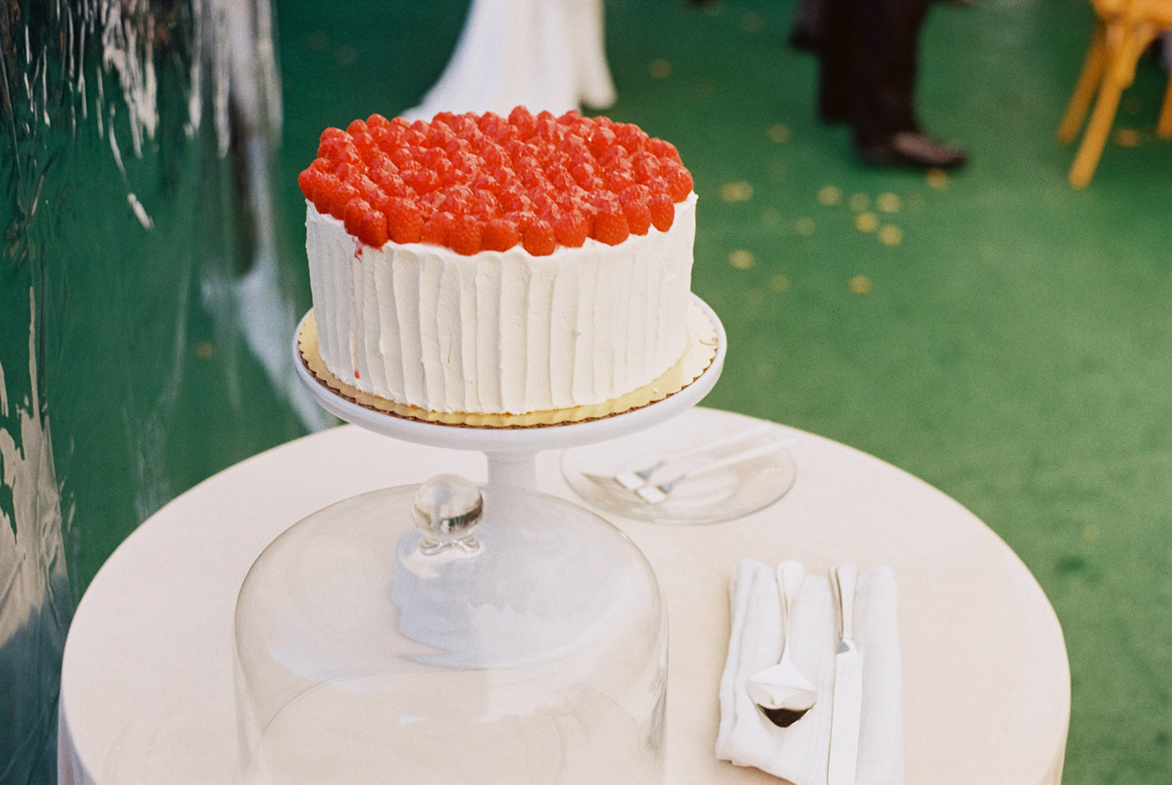 a single-tier wedding cake from Meringue Bakery & Cafe with raspberries on top