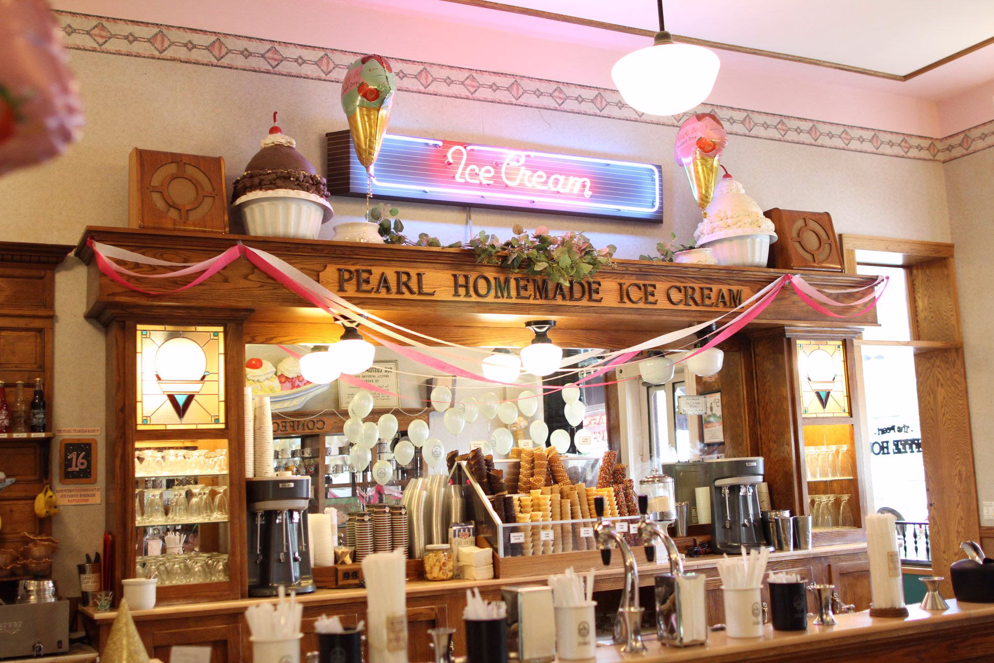 A retro ice cream parlor counter with milkshake supplies beneath a neon "Ice cream" sign and a main sign reading "Pearl Homemade Ice Cream."