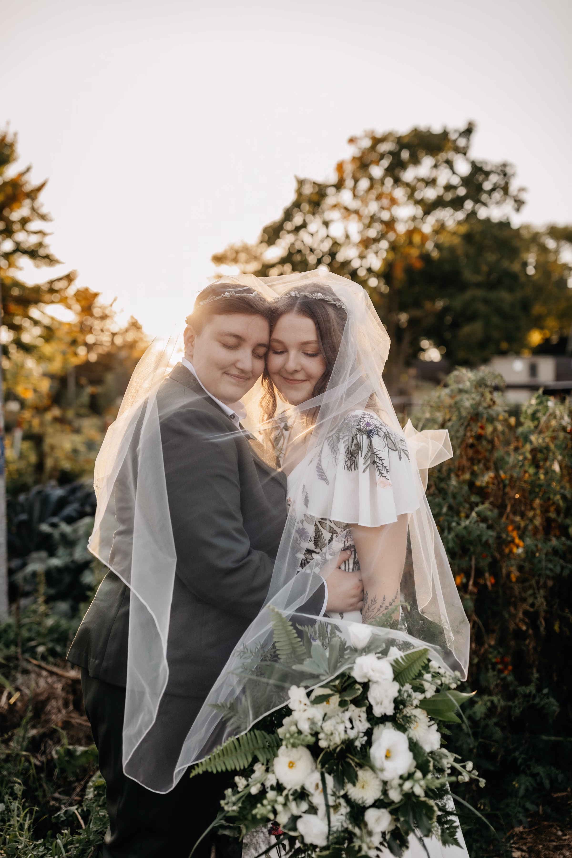 the brides embrace under a tulle veil for a romantic, sunset photo by Rhonda Rogers Photography