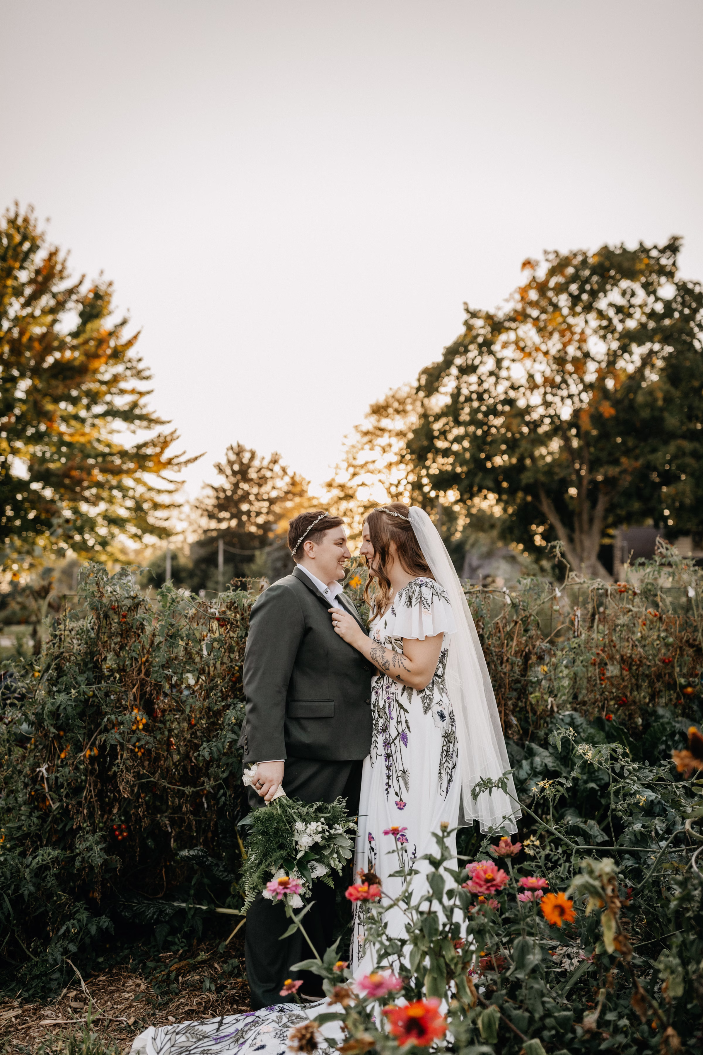 Sam and Janine embrace, smiling at one another, surrounded by Wisconsin wildflowers and greenery