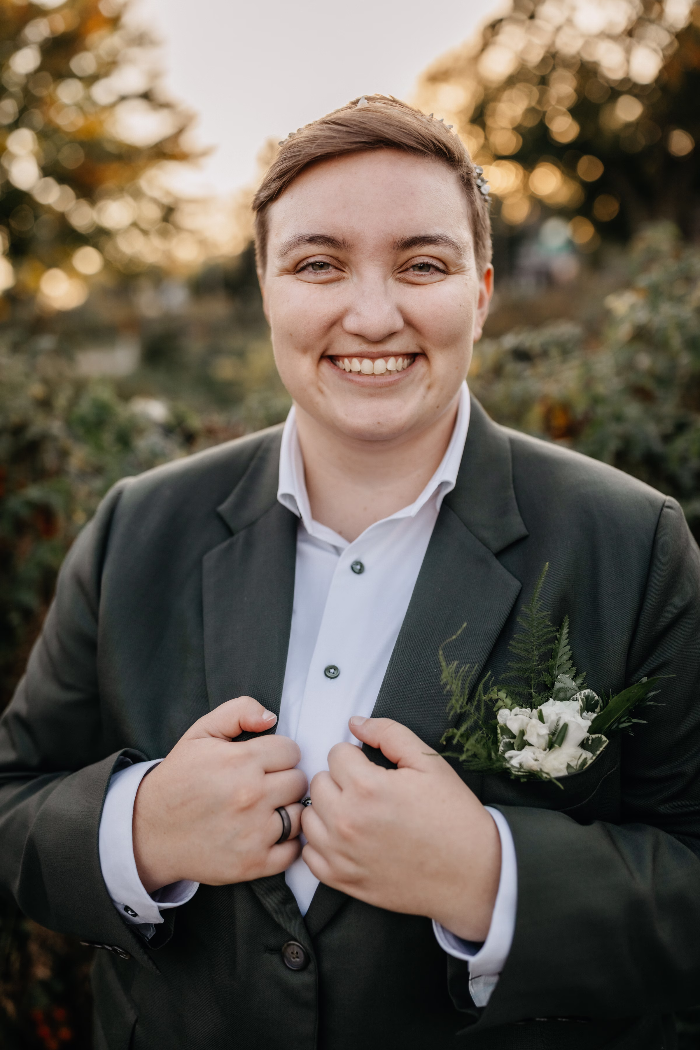 Janine smiles at the camera with bold hands on the lapel of her gray suit jacket