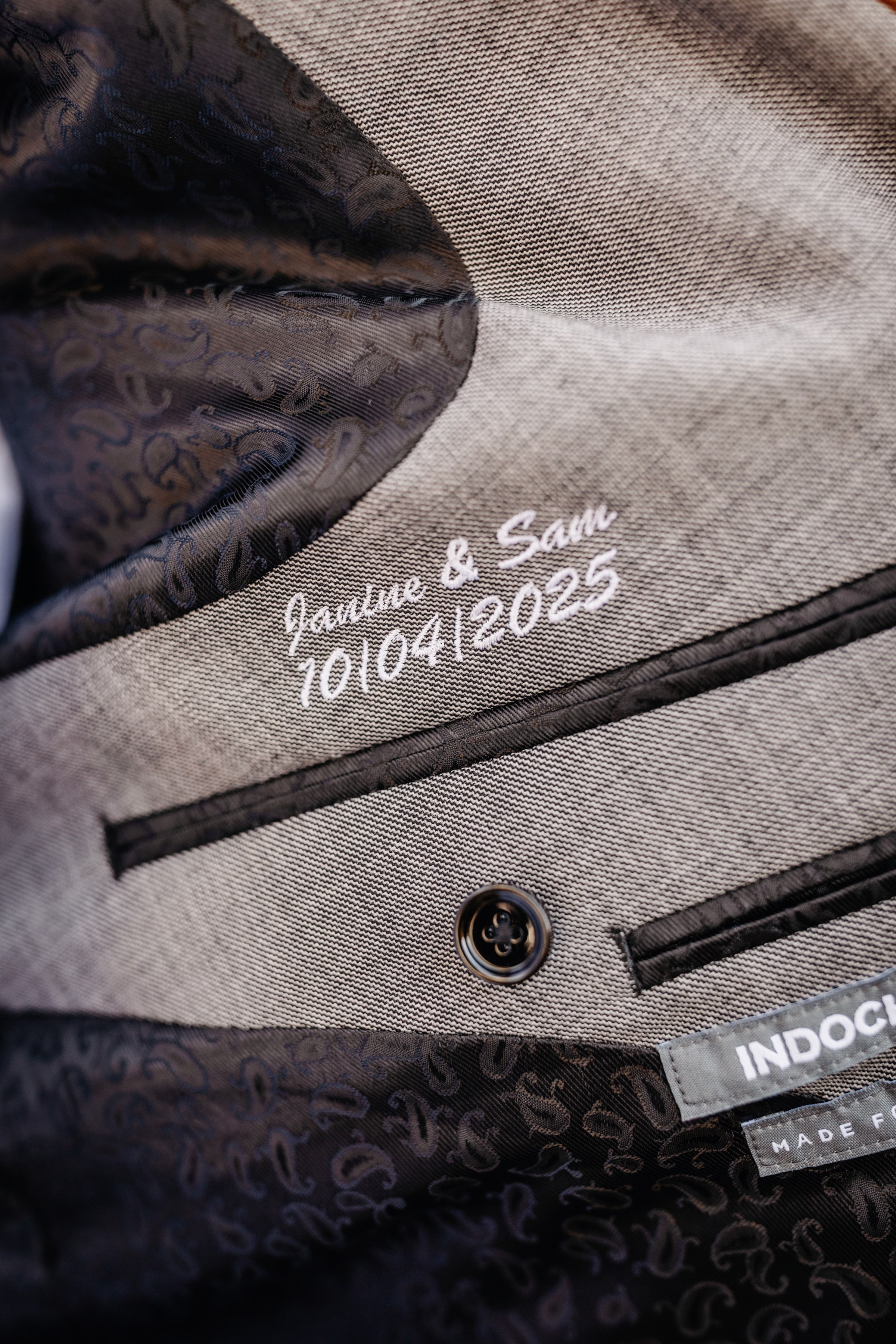 custom embroidered suit jacket showing the couple's names and wedding date: Janine & Sam, 10/04/2025