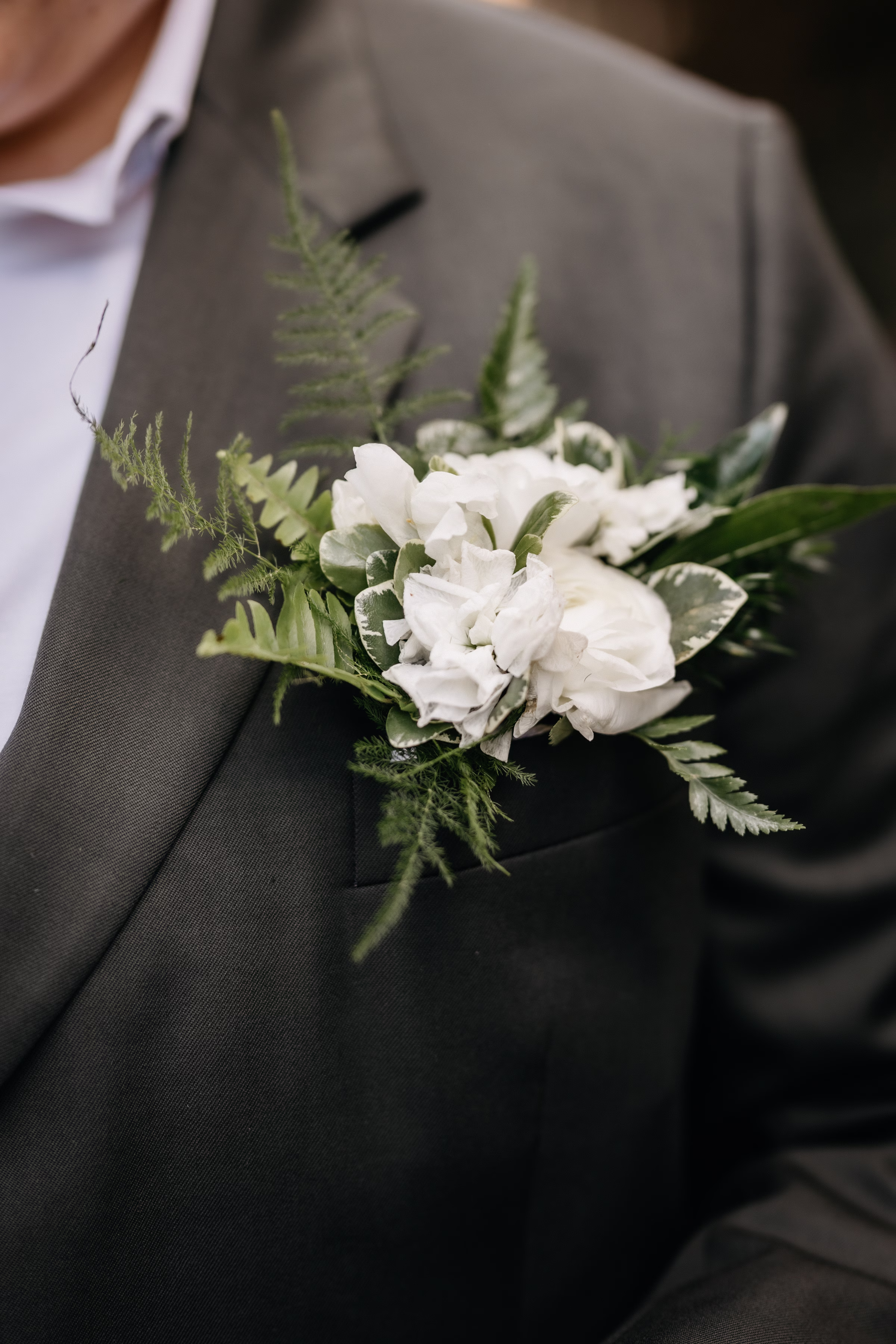 a close-up on a floral boutonniere of white florals and greenery