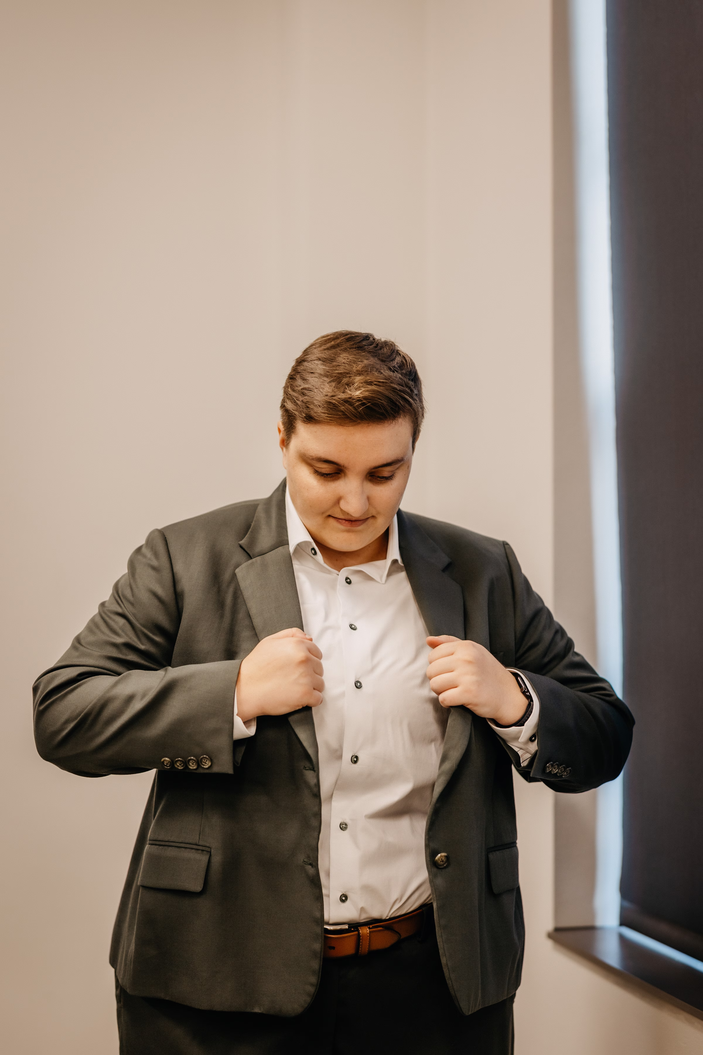 a bride prepares for her wedding day, putting on her suit jacket