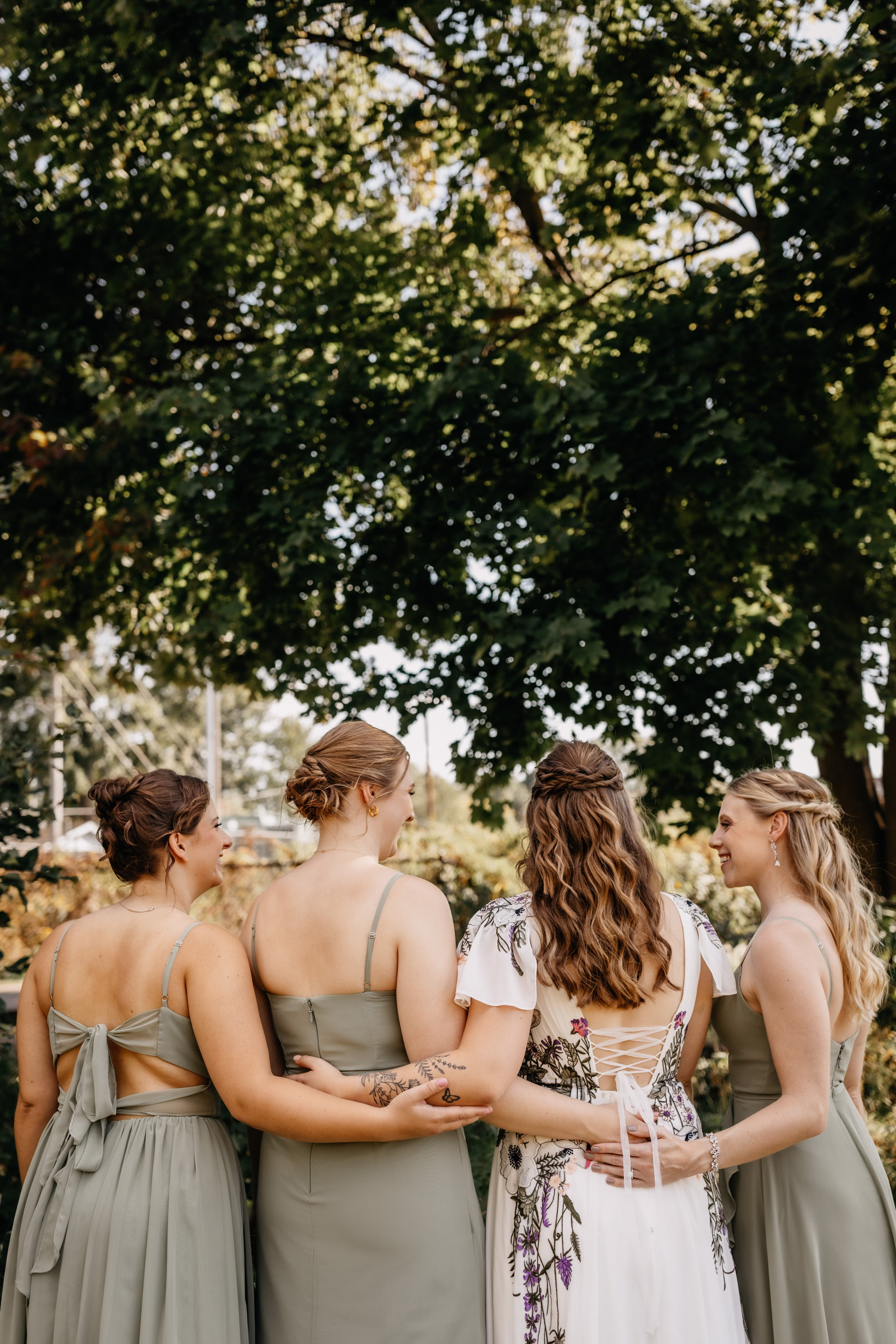 a photo of Sam standing with her wedding party members dressed in sage green, showing their curled half-updo or updo hairstyles