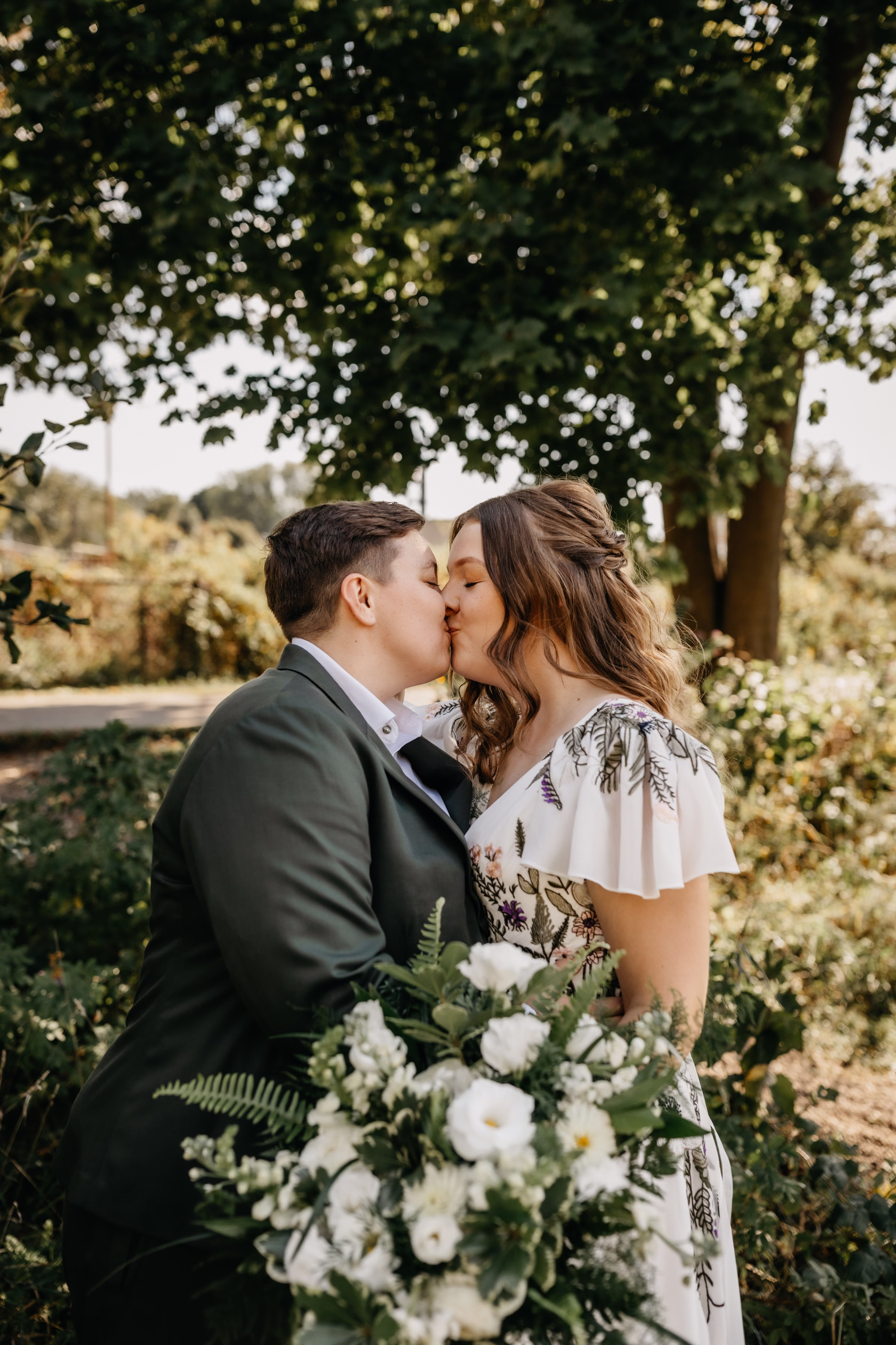 Sam and Janine share a kiss outside Goodman Center, surrounded by sunshine and greenery