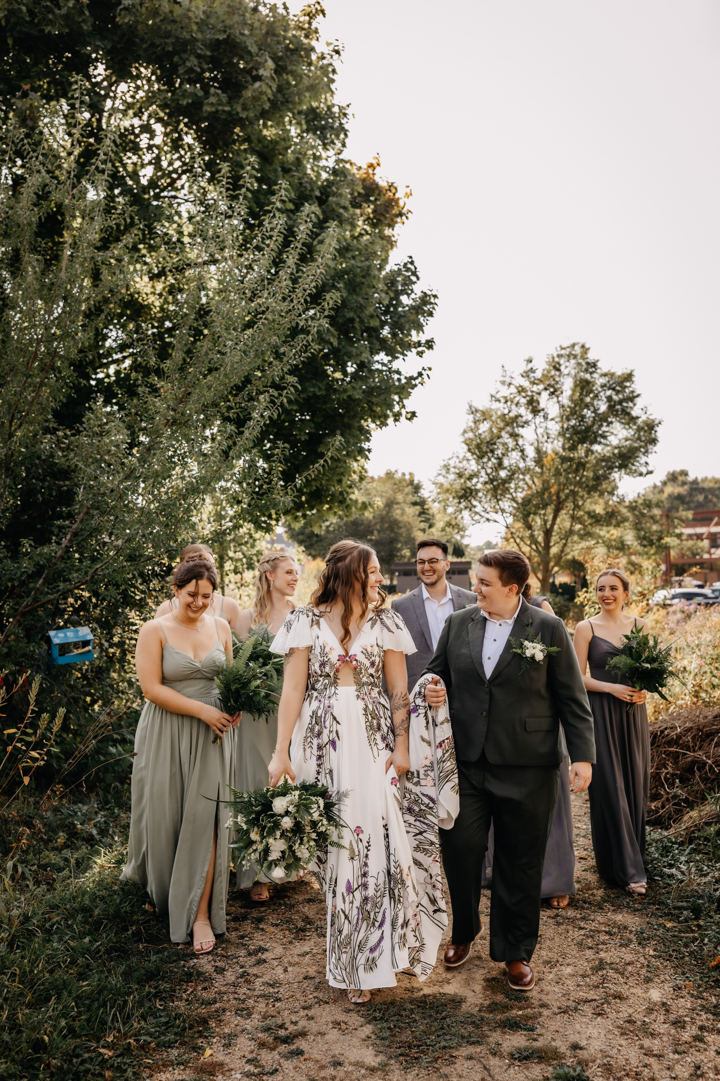 the couple candidly walks as their wedding party follows behind