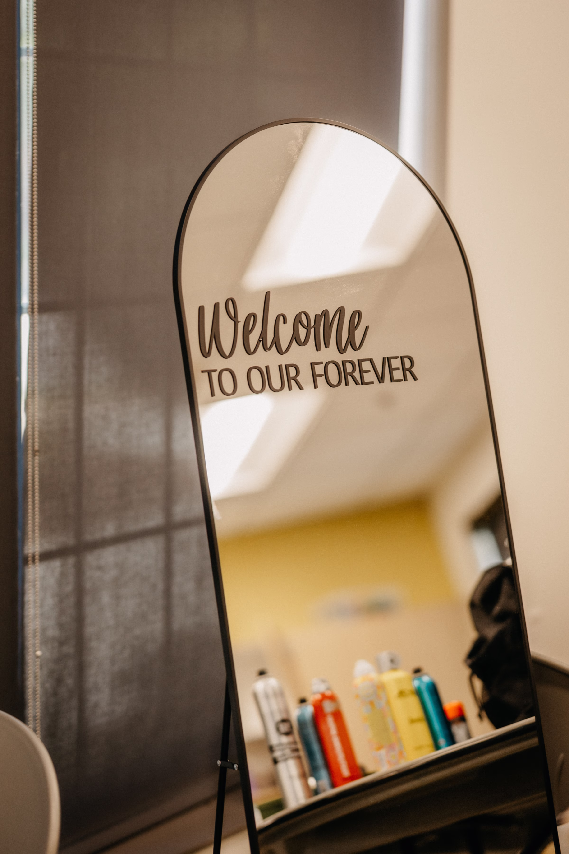 a wedding welcome sign that says "welcome to our forever," installed on an arched mirror