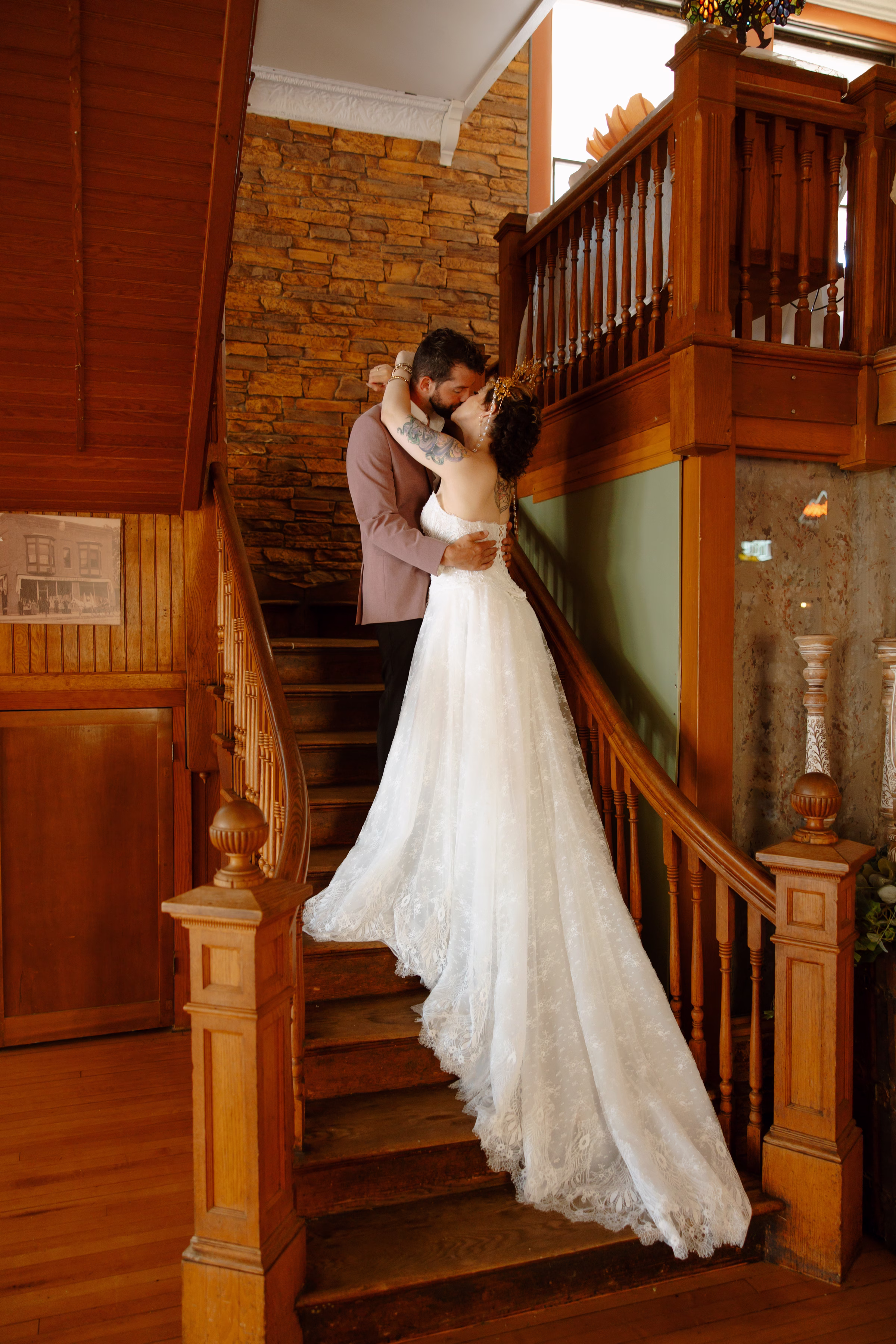 a bride and groom share a kiss on the wooden staircase at B's Place Event Venue in West Salem, Wisconsin