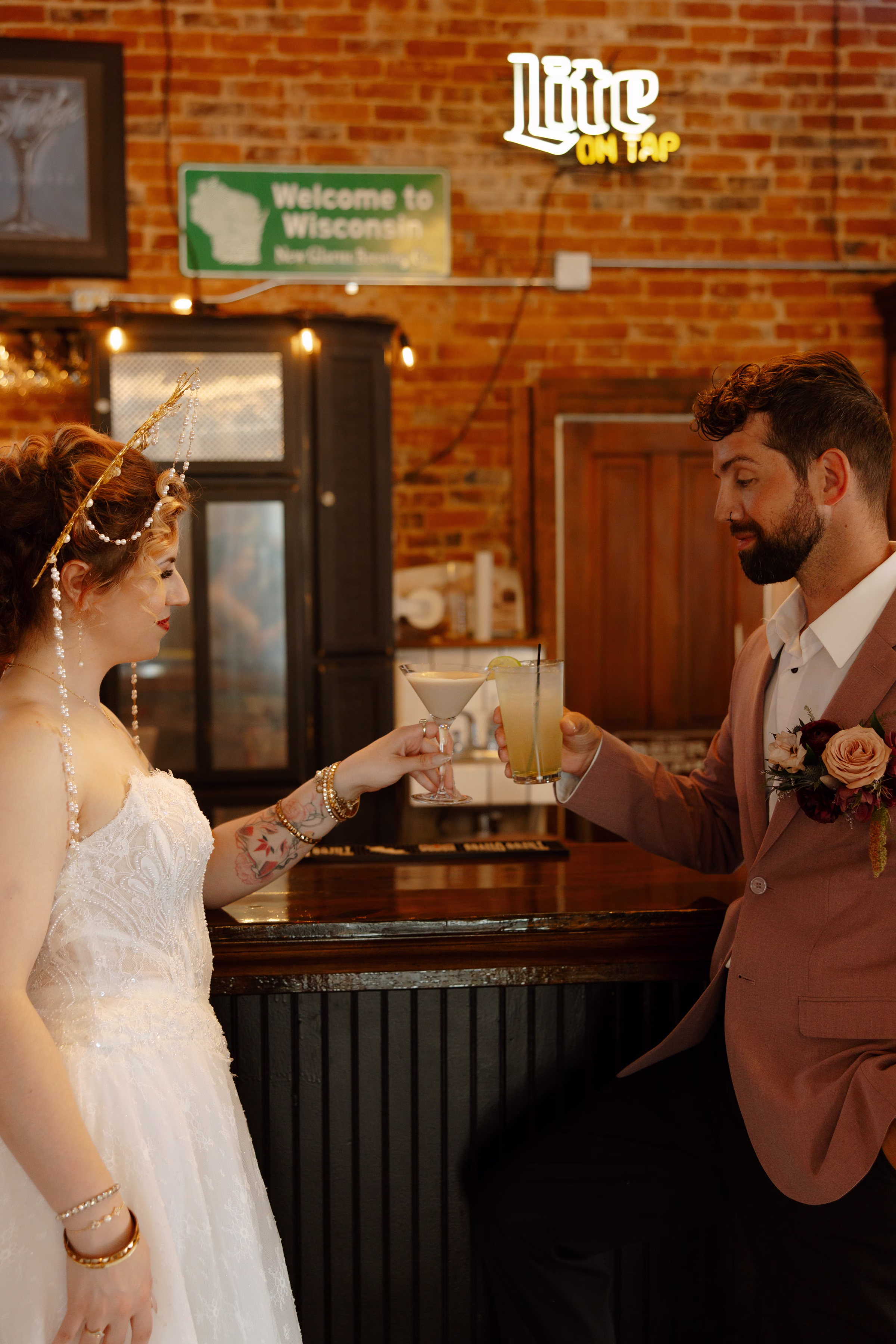 a bride and groom toast glasses beside the bar at B's Place Event Venue in West Salem, Wisconsin