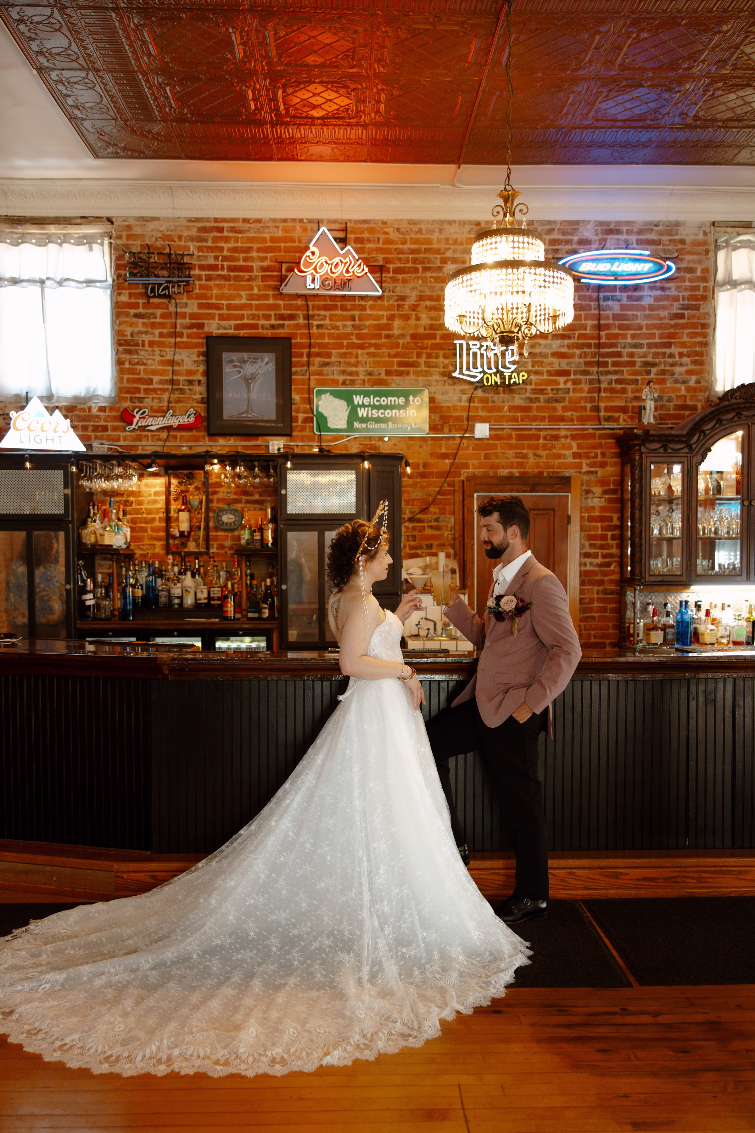 a bride and groom toast glasses beside the bar at B's Place Event Venue in West Salem, Wisconsin
