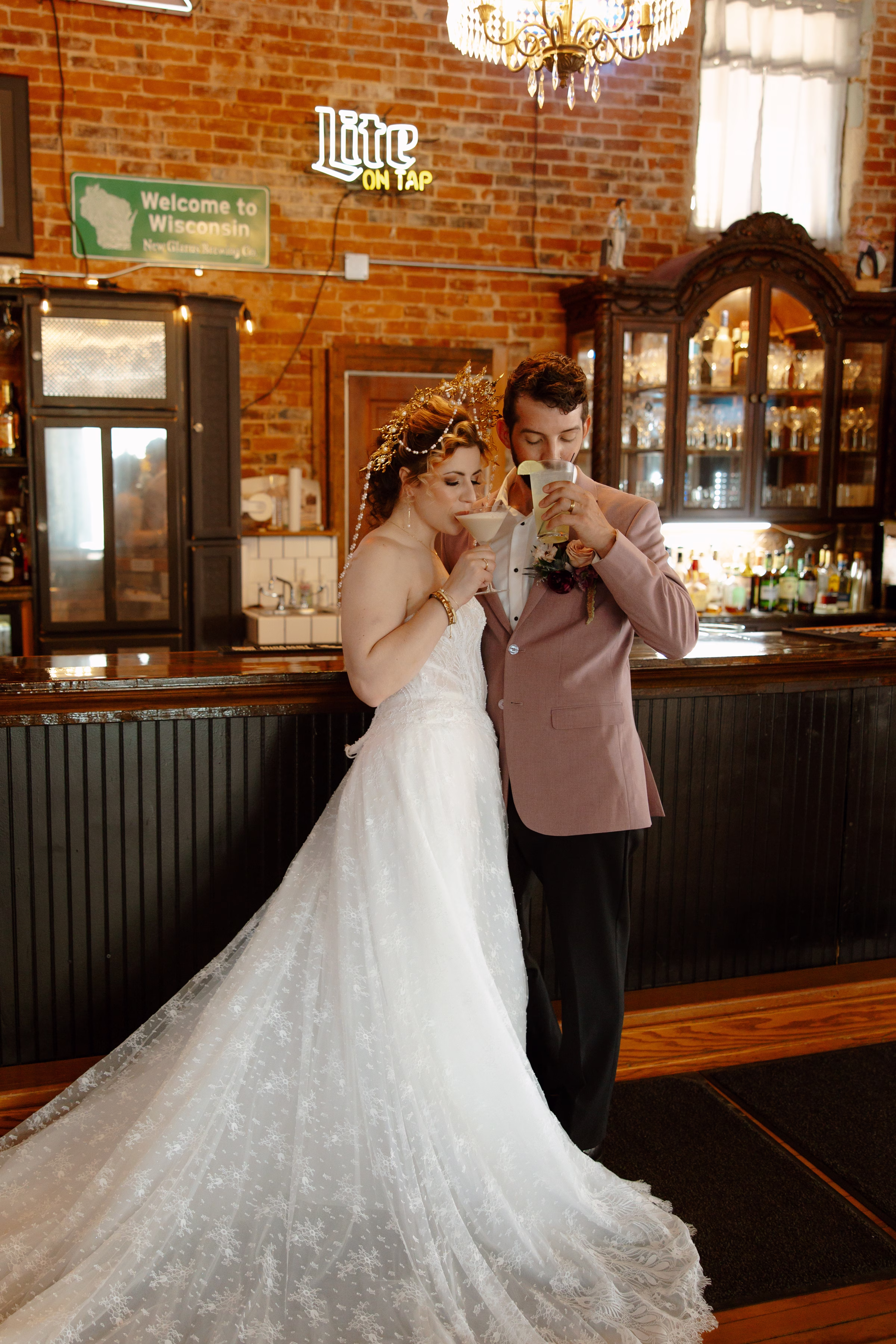 a bride and groom sip drinks beside the bar at B's Place Event Venue in West Salem, Wisconsin