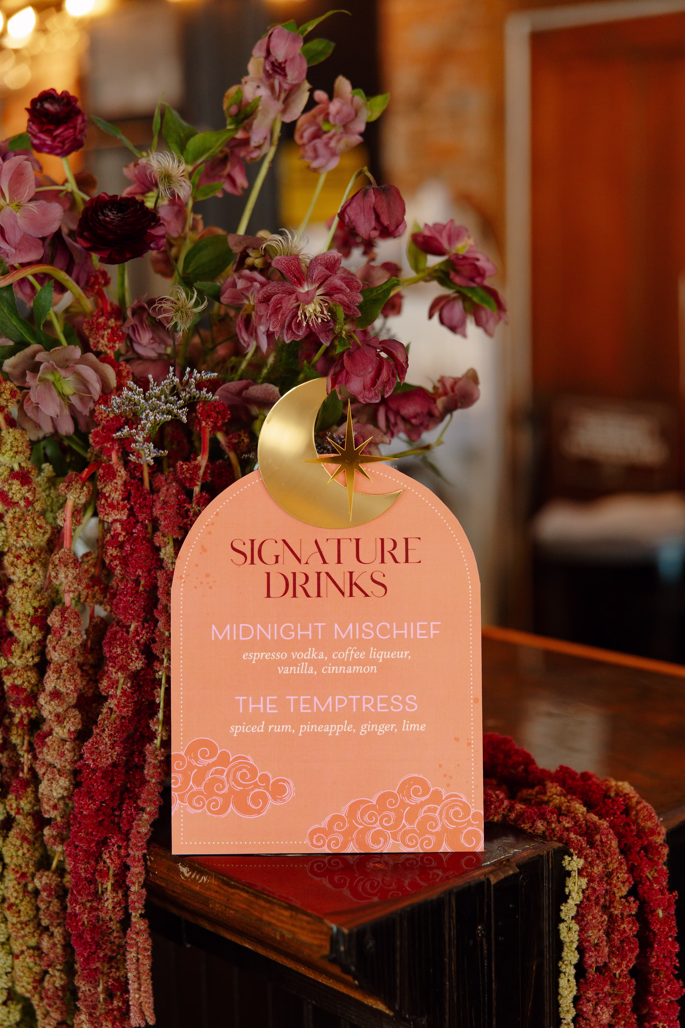 a detail photo of arched, orange drink signage by LK Bridal Studio, with acrylic moon on the top