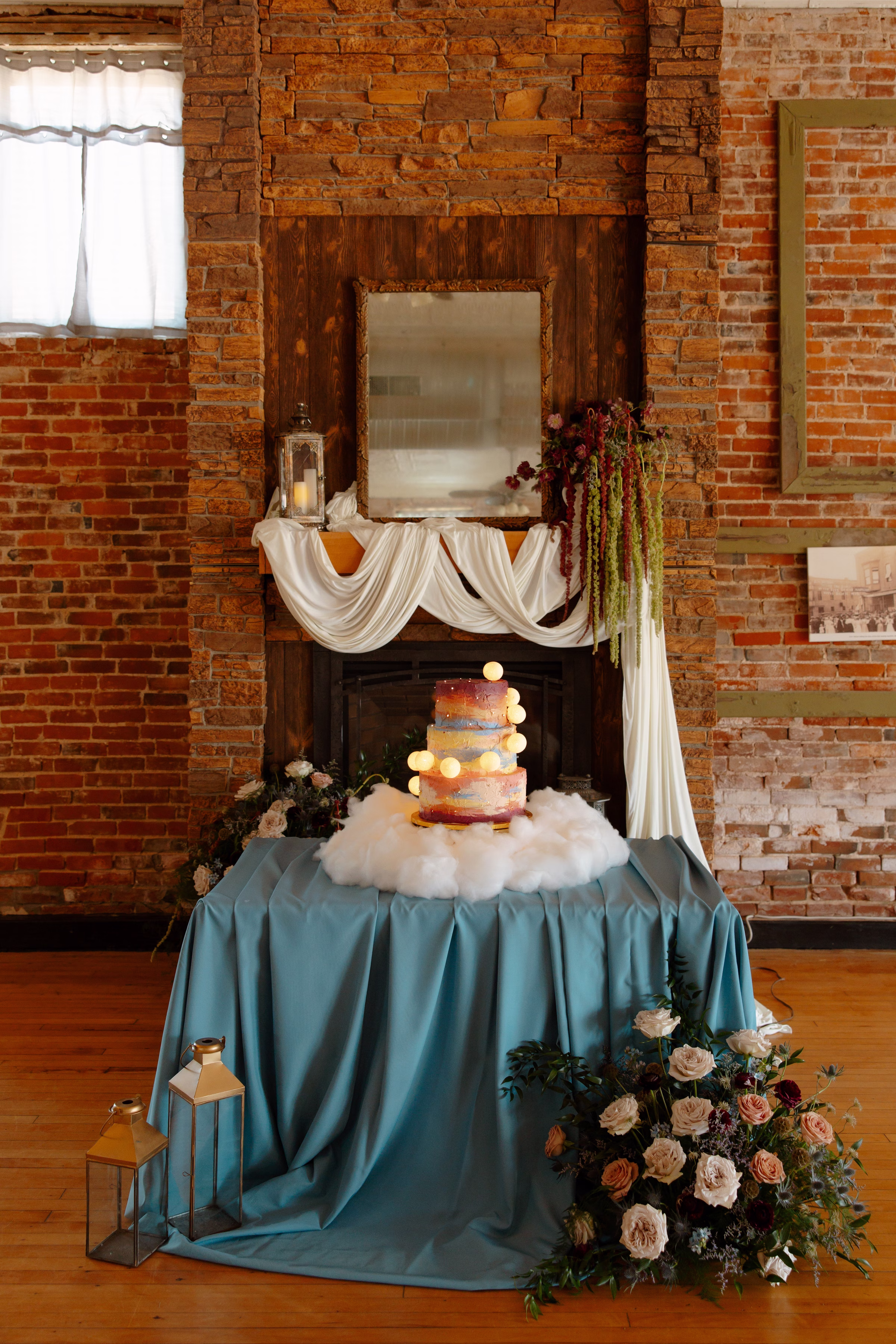 a display table featuring a celestial summer sunset wedding cake by Cowboy David's Bakery with painted frosting and playful moons