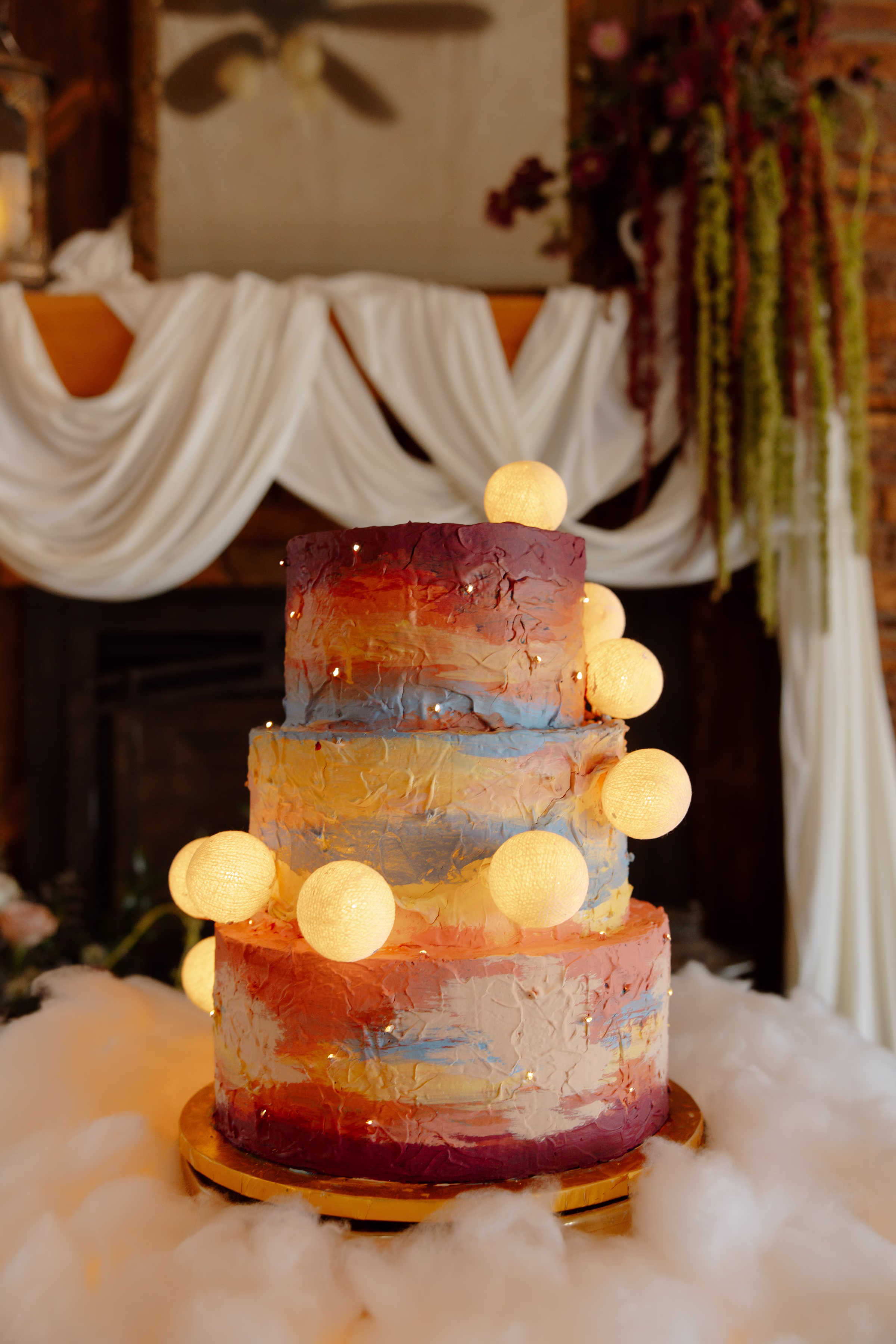 a close up photo of a celestial summer sunset wedding cake by Cowboy David's Bakery with painted frosting and playful moons