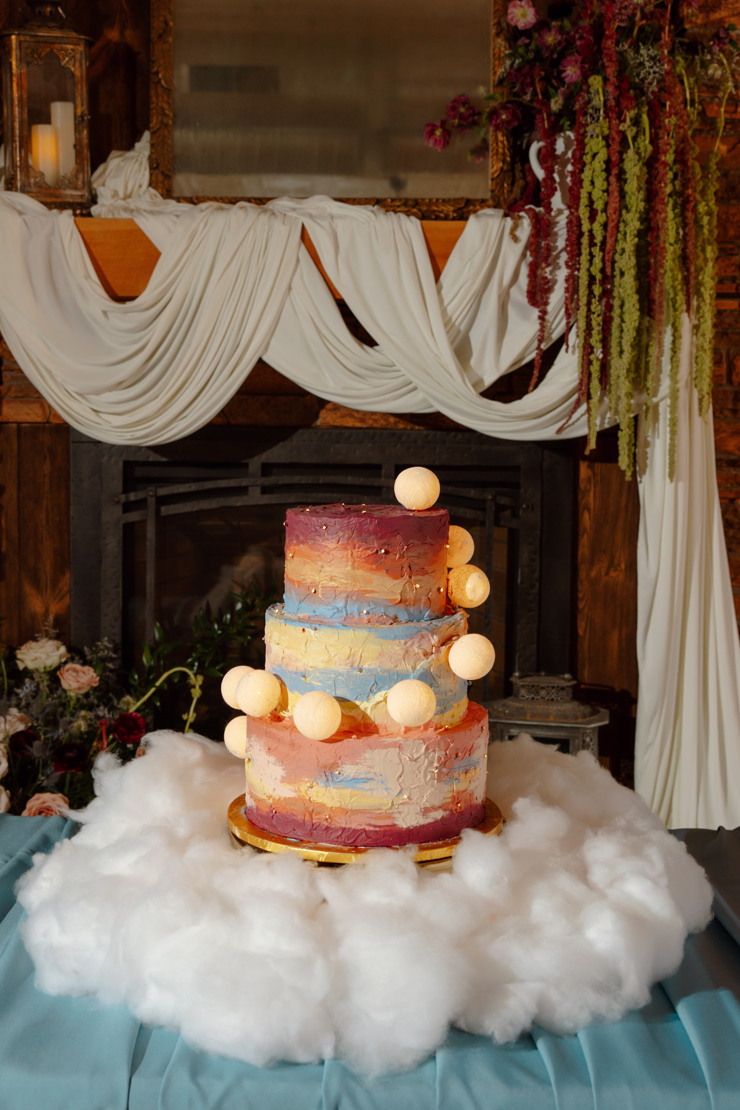 a celestial summer sunset wedding cake by Cowboy David's Bakery with painted frosting and playful moons. The cake is displayed on faux clouds