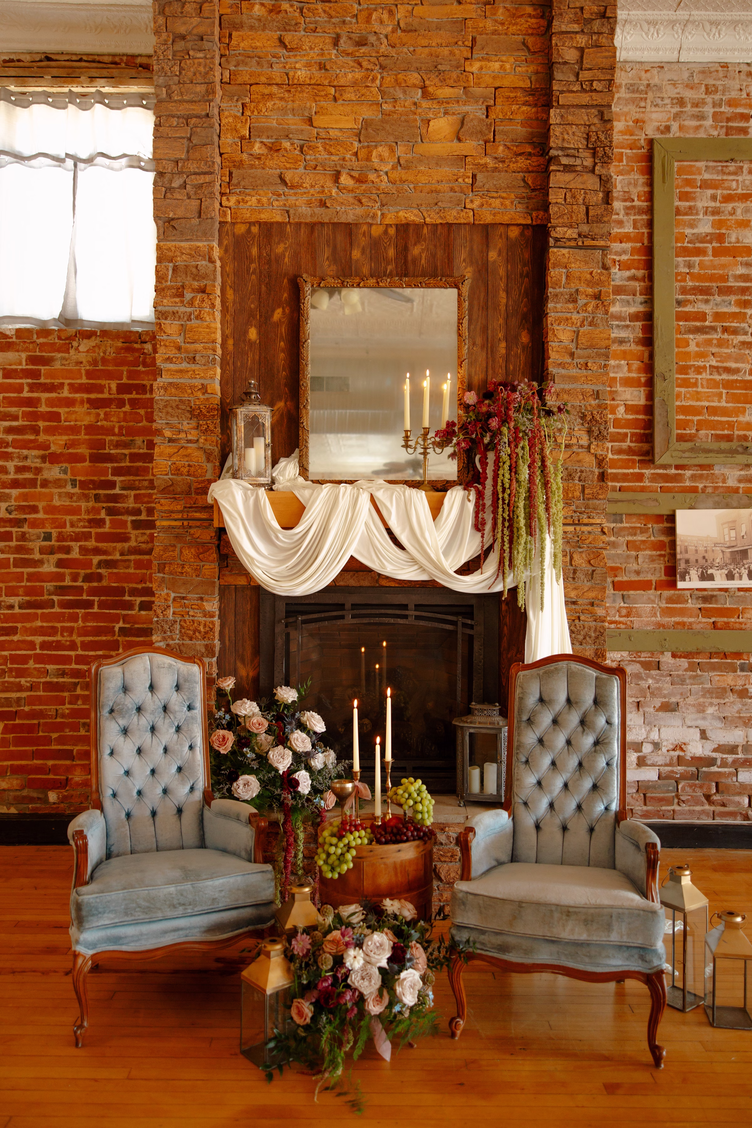 a wedding lounge setup at B's Place in West Salem, Wisconsin featuring florals, dusty blue velvet chairs, candles, draping, and other décor