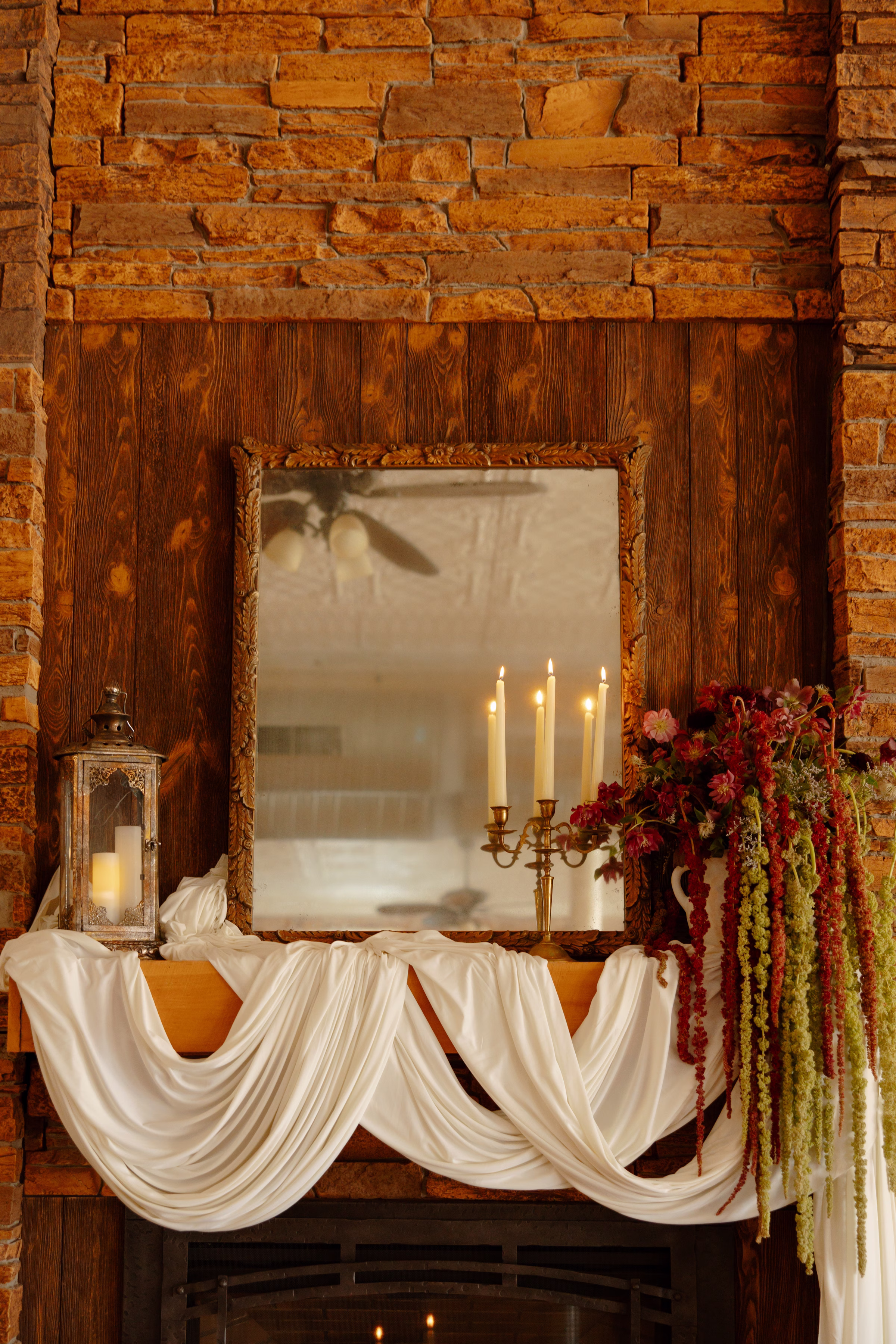 a detail photo of the draping and florals along the fireplace in the lounge at B's Place in West Salem, Wisconsin. Florals consist of mostly red and green amaranthus