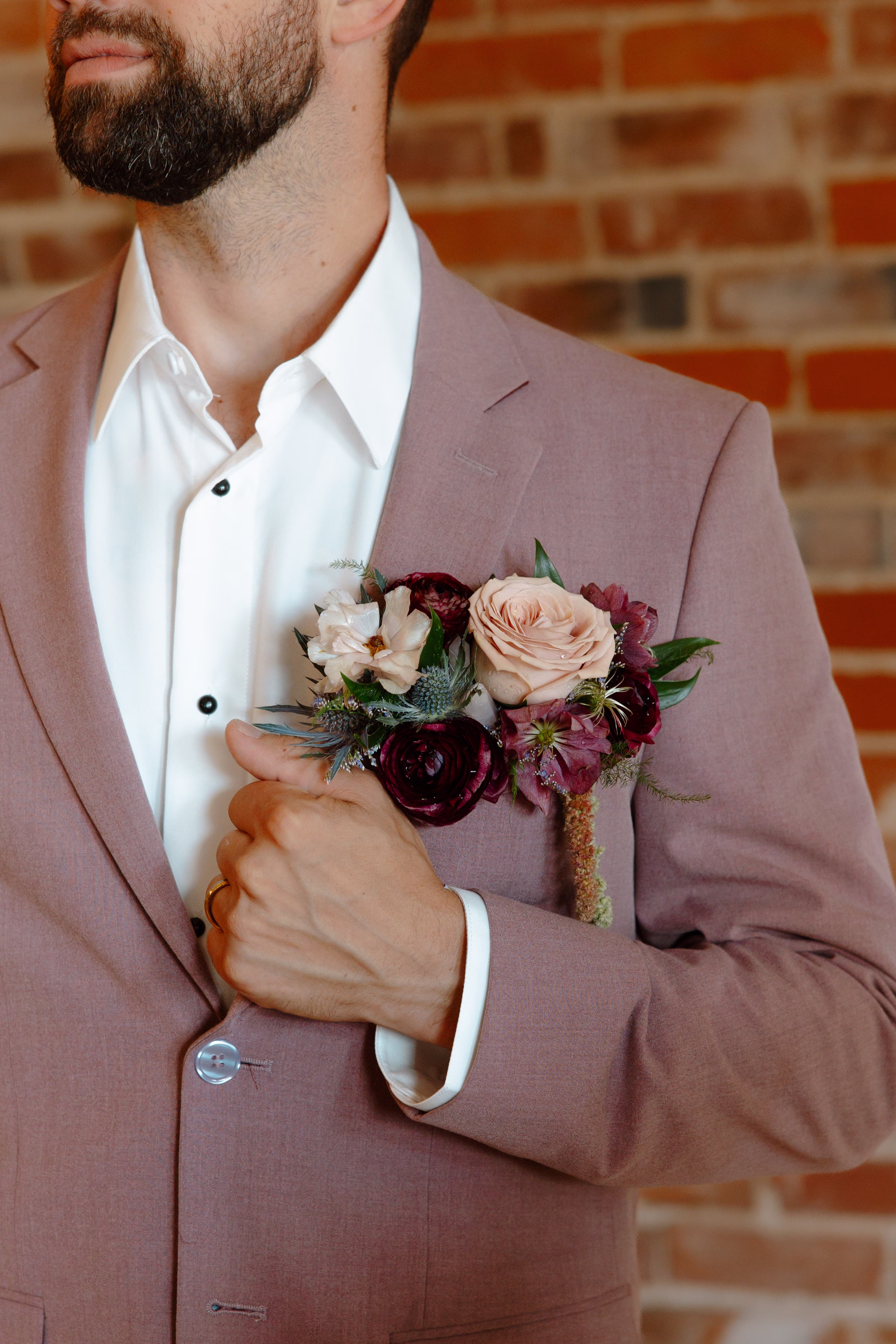 a detail photo of the groom's dusty mauve suit jacket from Charlotte's Bridal & Formal Wear and floral boutonniere by Bloom & Knot LLC