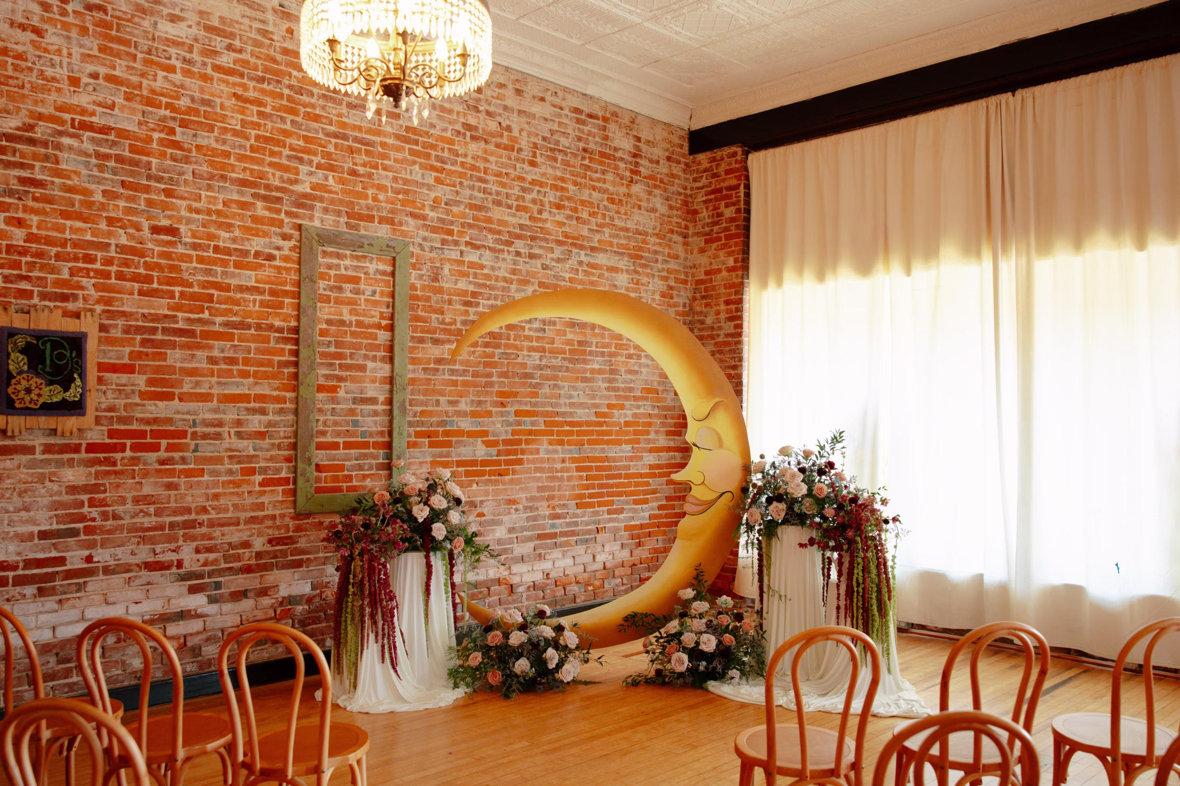 celestial ceremony smiling crescent-moon backdrop a B's Place Event Venue in West Salem, Wisconsin, surrounded by ground floral installations and floral pedestals