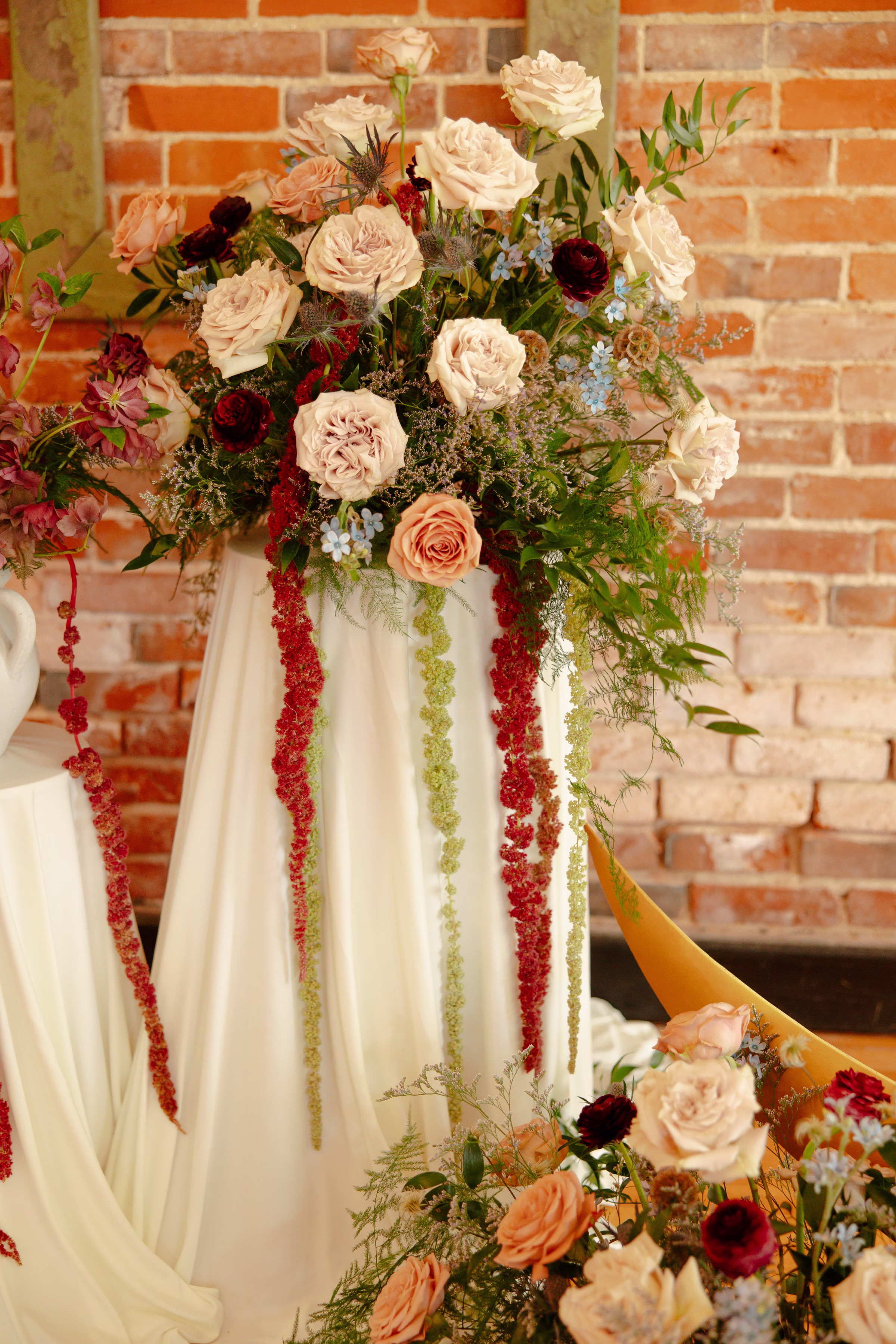 a straight forward angle of the ceremony florals placed atop pedestals with white drapery