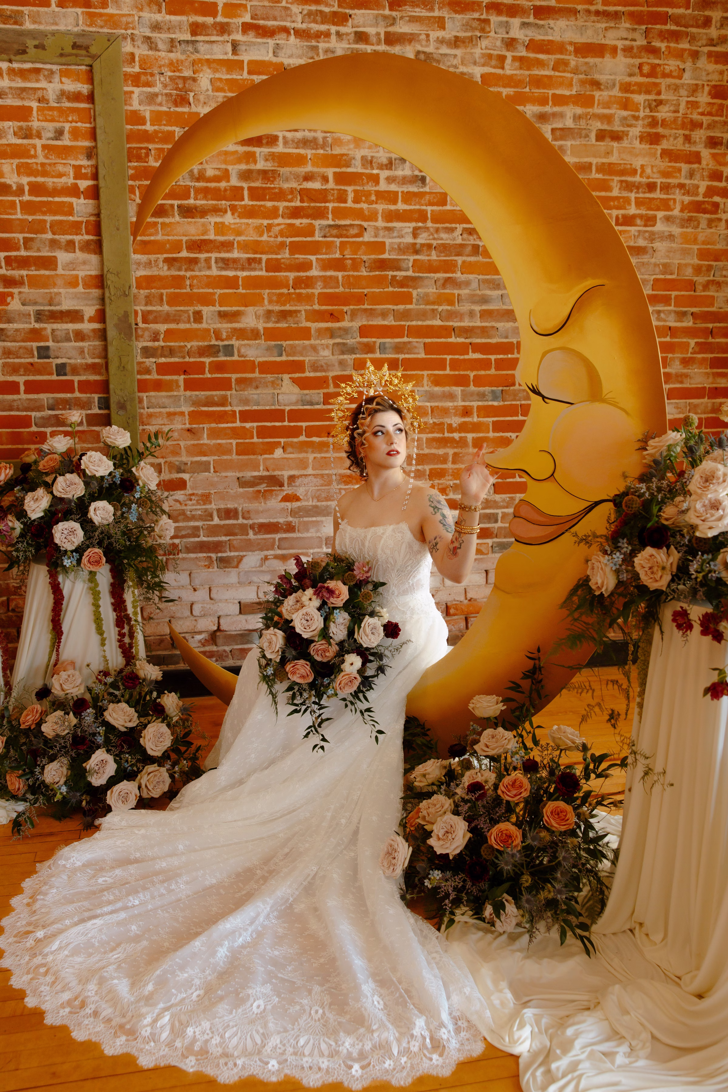 the bride model sits on the crescent moon ceremony backdrop, wistfully looking up