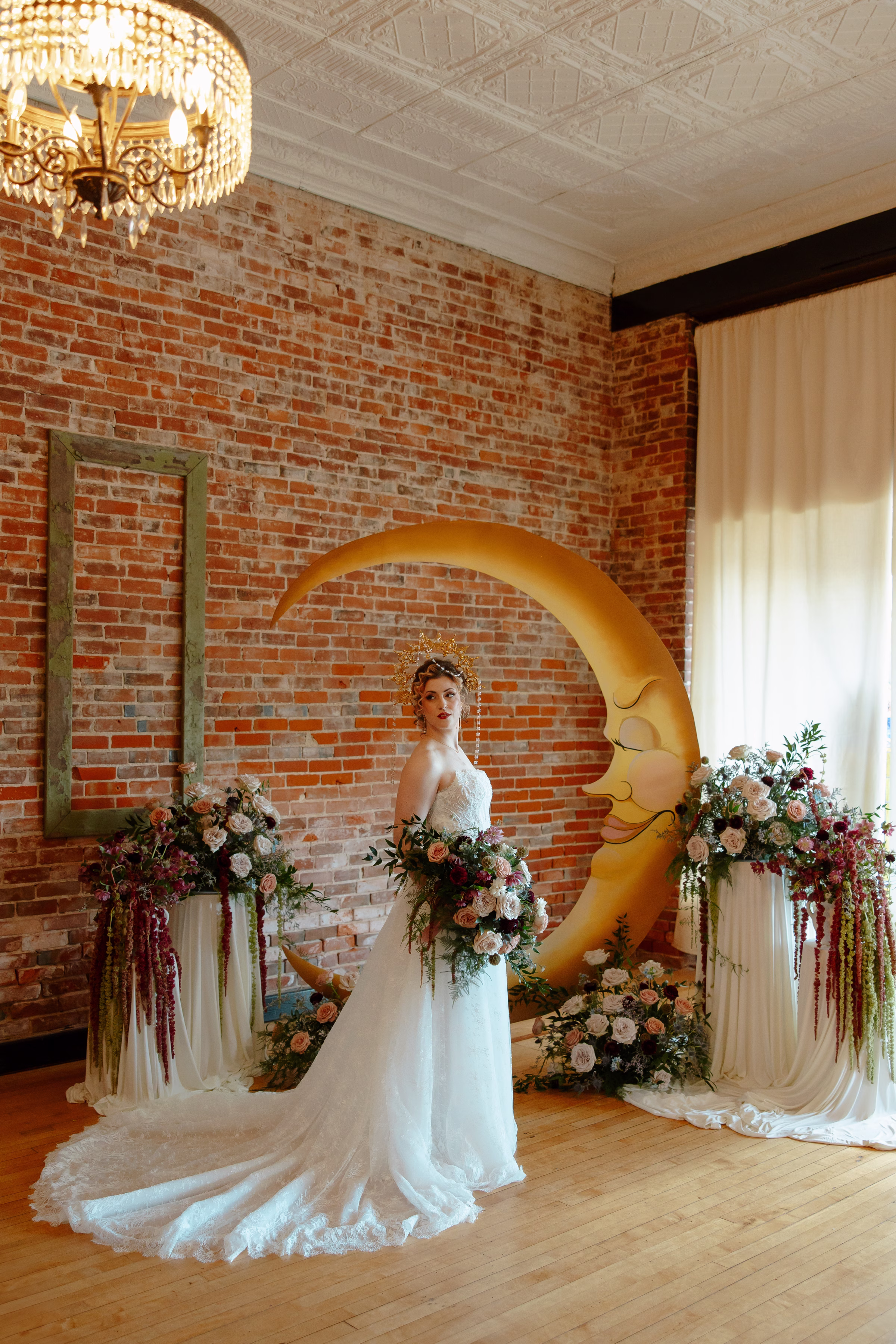 the bride holds her bouquet, posing in front of the crescent moon celestial-inspired ceremony at B's Place Event Venue in West Salem, Wisconsin