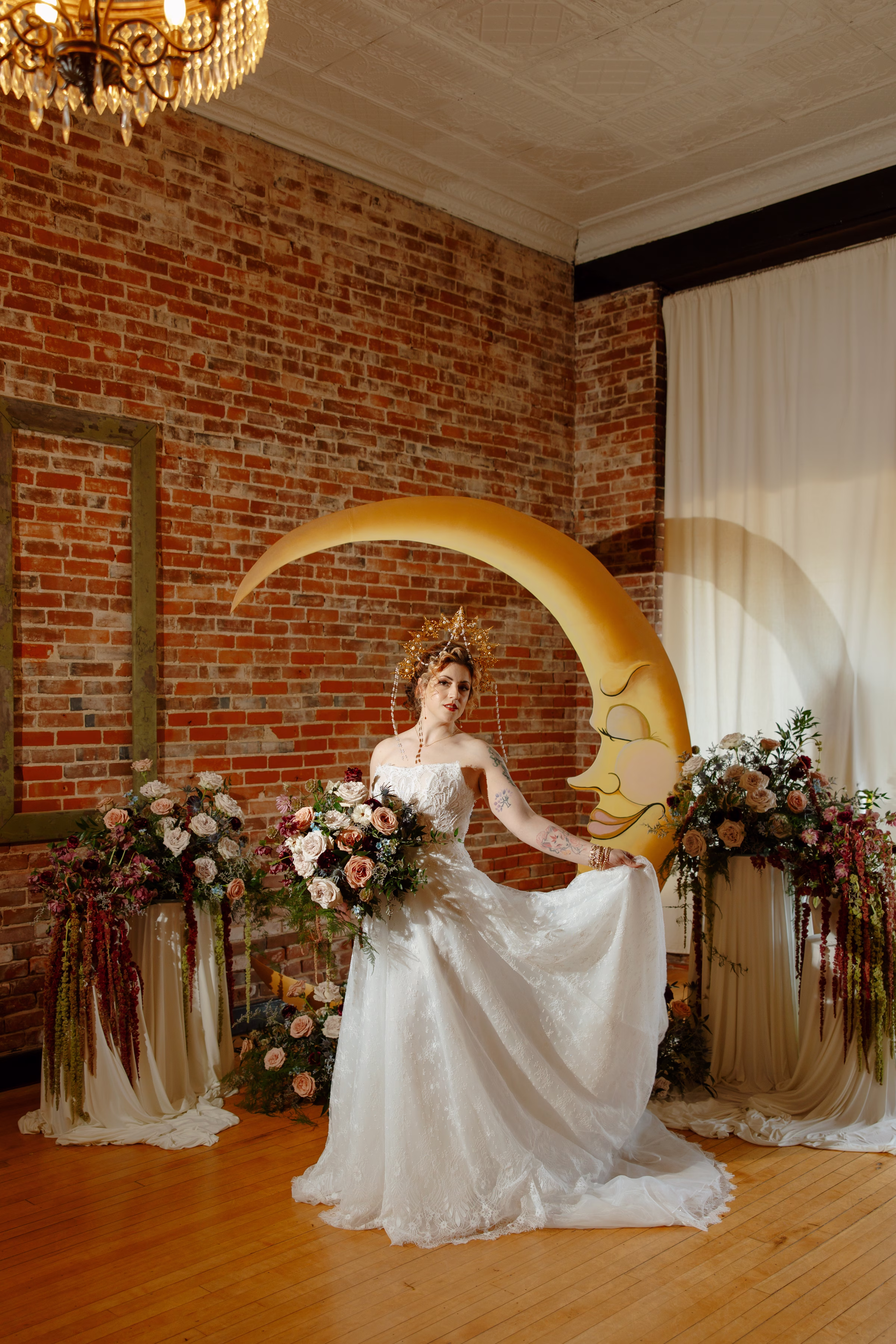 the bride stands at the celestial ceremony, posing with one hand holding up the skirt of her dress from Charlotte's Bridal & Formal Wear