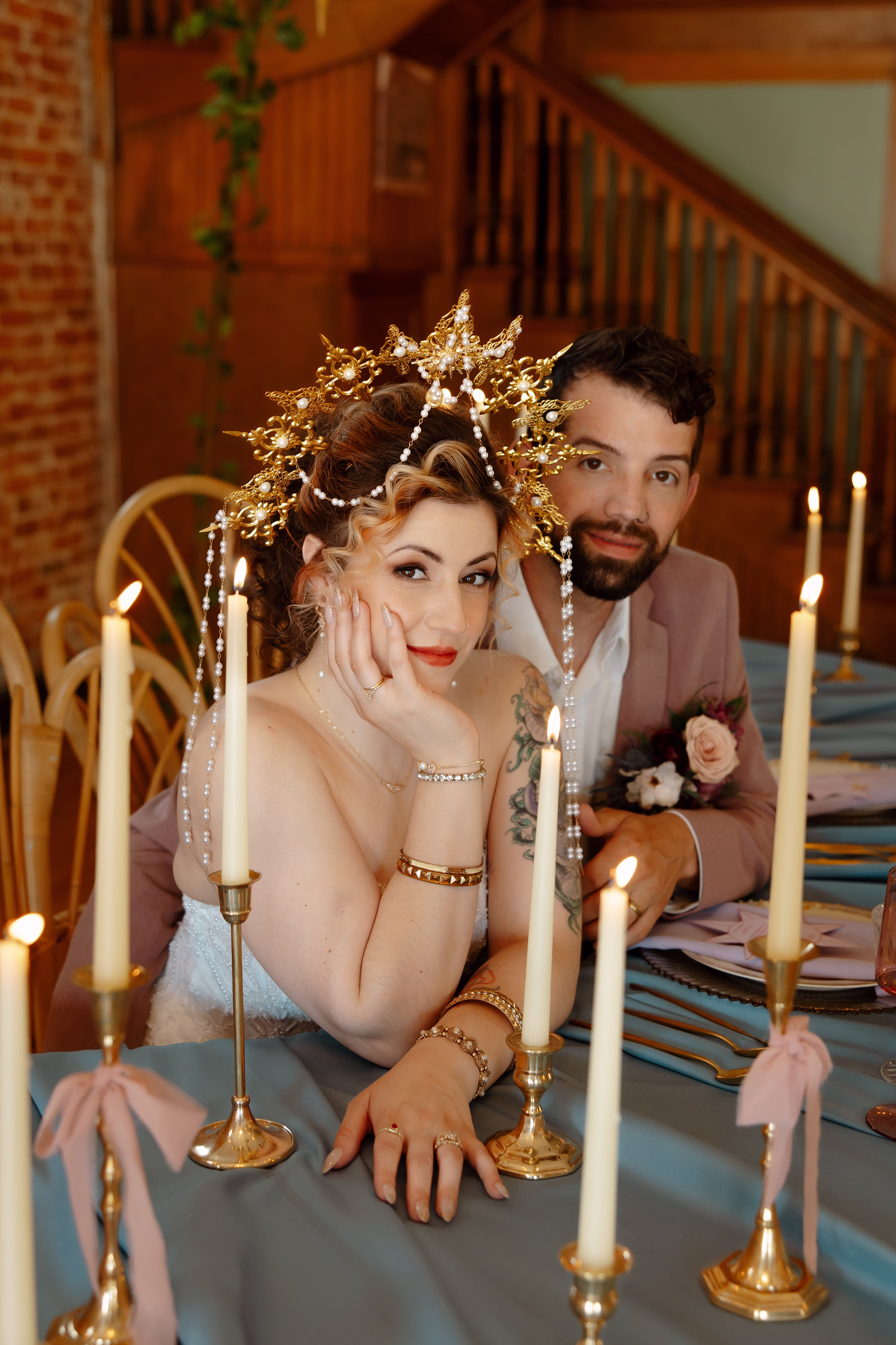 the couple sits at the sweetheart table surrounded by lit candles