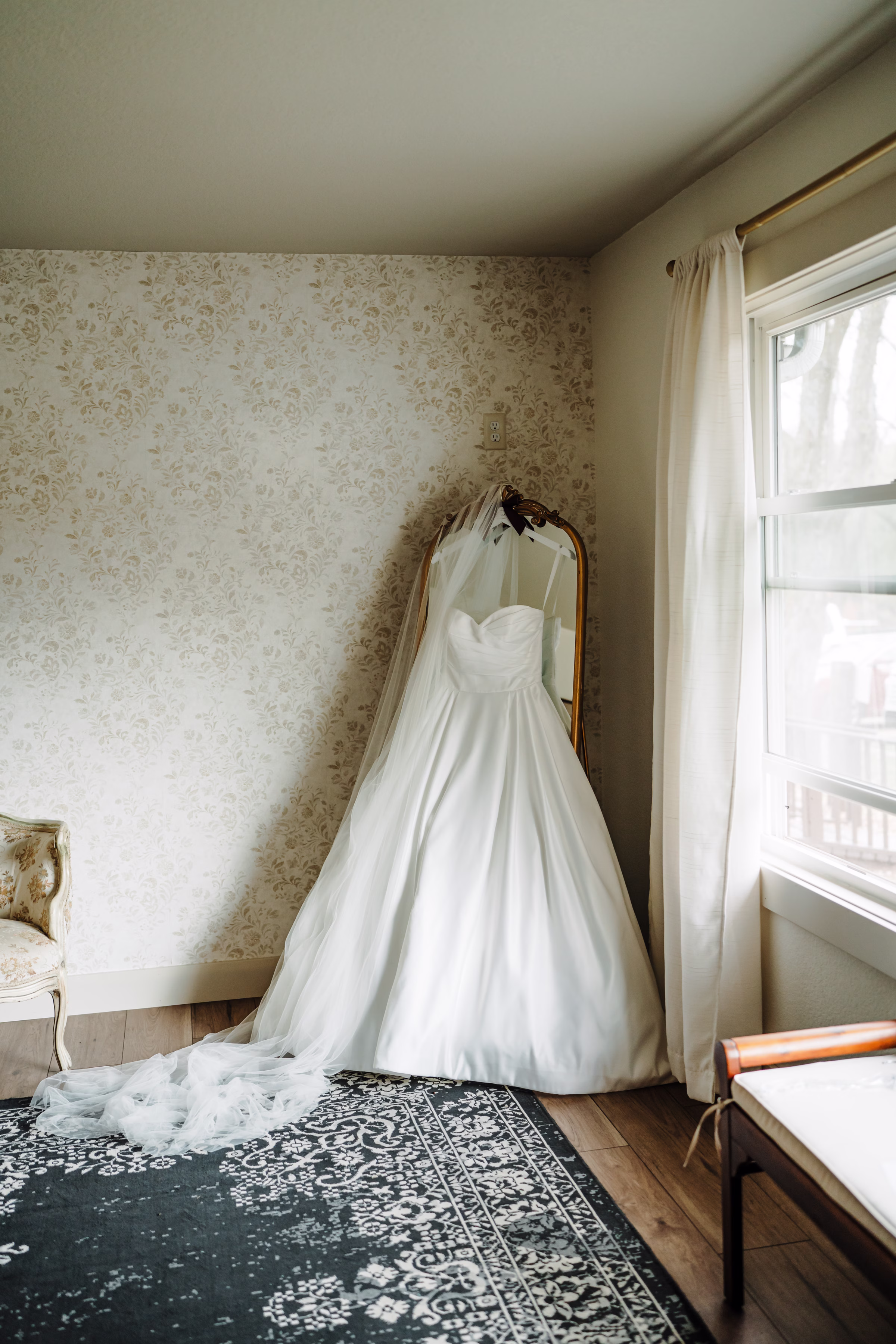 scenic fall wedding winnebago springs minnesota bridal preparation 3494 - An Elegant Fall Wedding at Winnebago Springs | Emma & Tyler an A-line wedding dress and veil from Charlotte's Bridal & Formal Wear is hung from a vintage mirror
