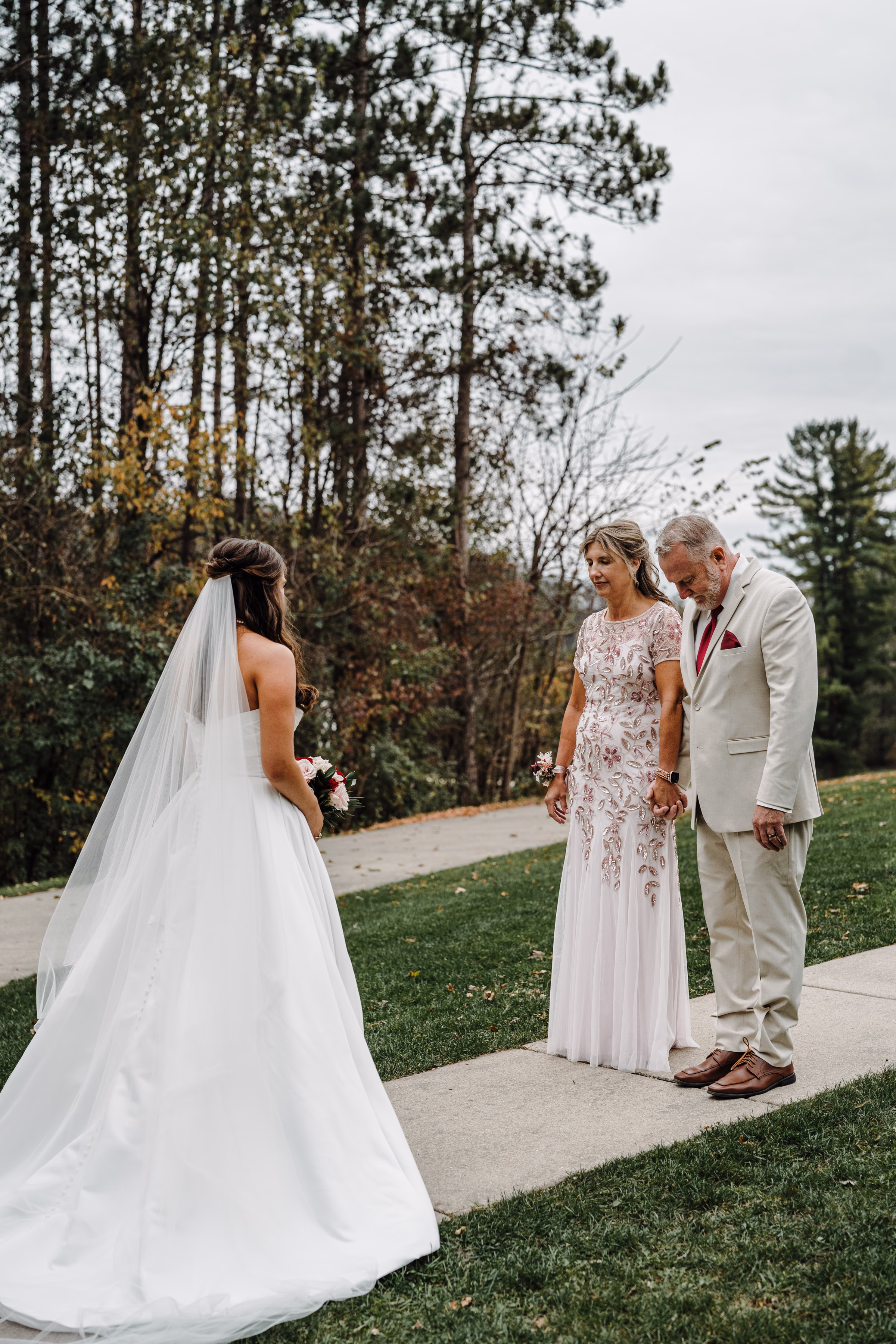 scenic fall wedding winnebago springs minnesota first look 0658 - An Elegant Fall Wedding at Winnebago Springs | Emma & Tyler mother and father of the bride close their eyes and hold hands, preparing for a first look of their daughter as a bride