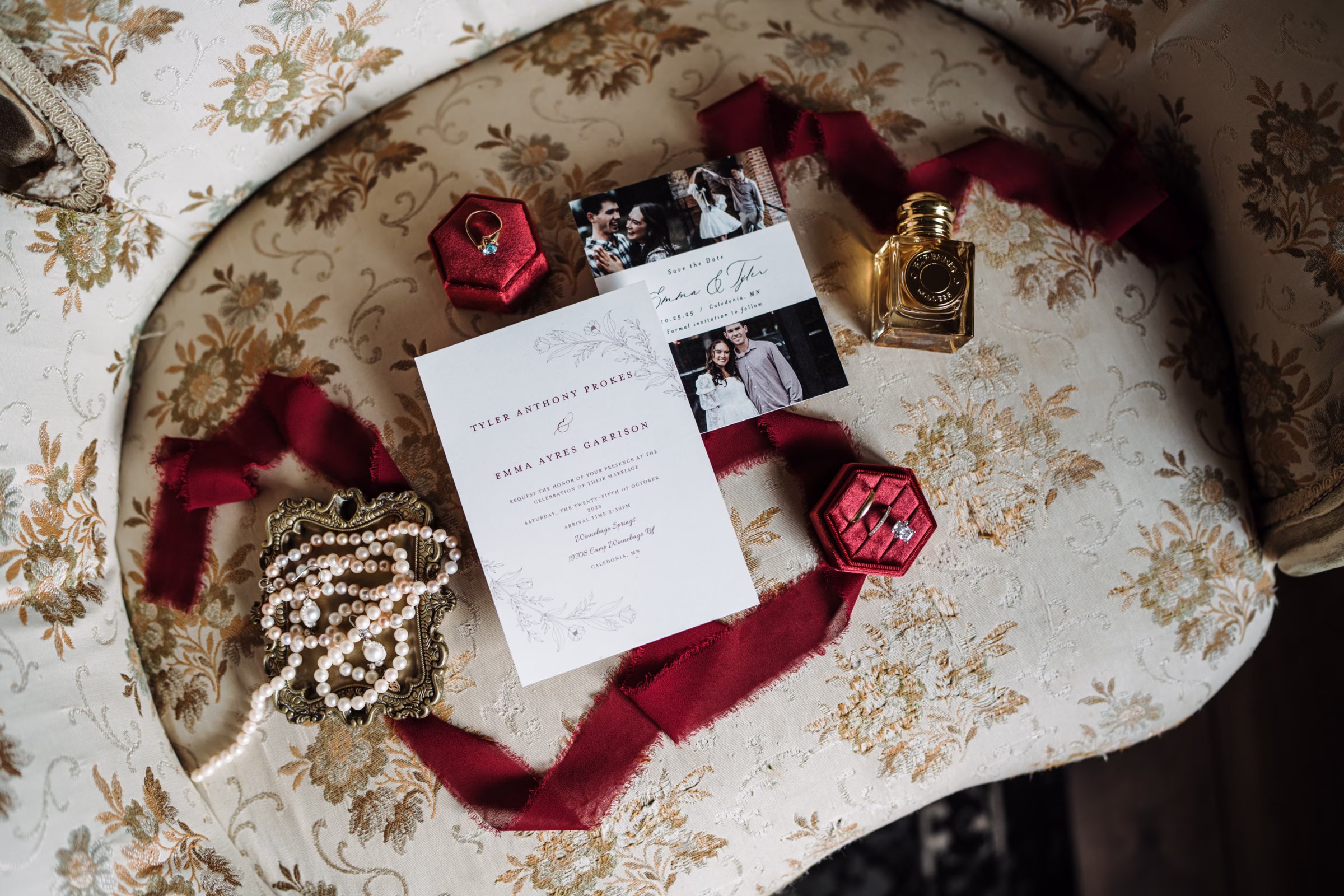 scenic fall wedding winnebago springs minnesota stationery details 3415 - An Elegant Fall Wedding at Winnebago Springs | Emma & Tyler fall wedding stationery featuring engagement photos sits on a vintage patterned chair. The stationery is surrounded by rings, jewelry, and perfume details