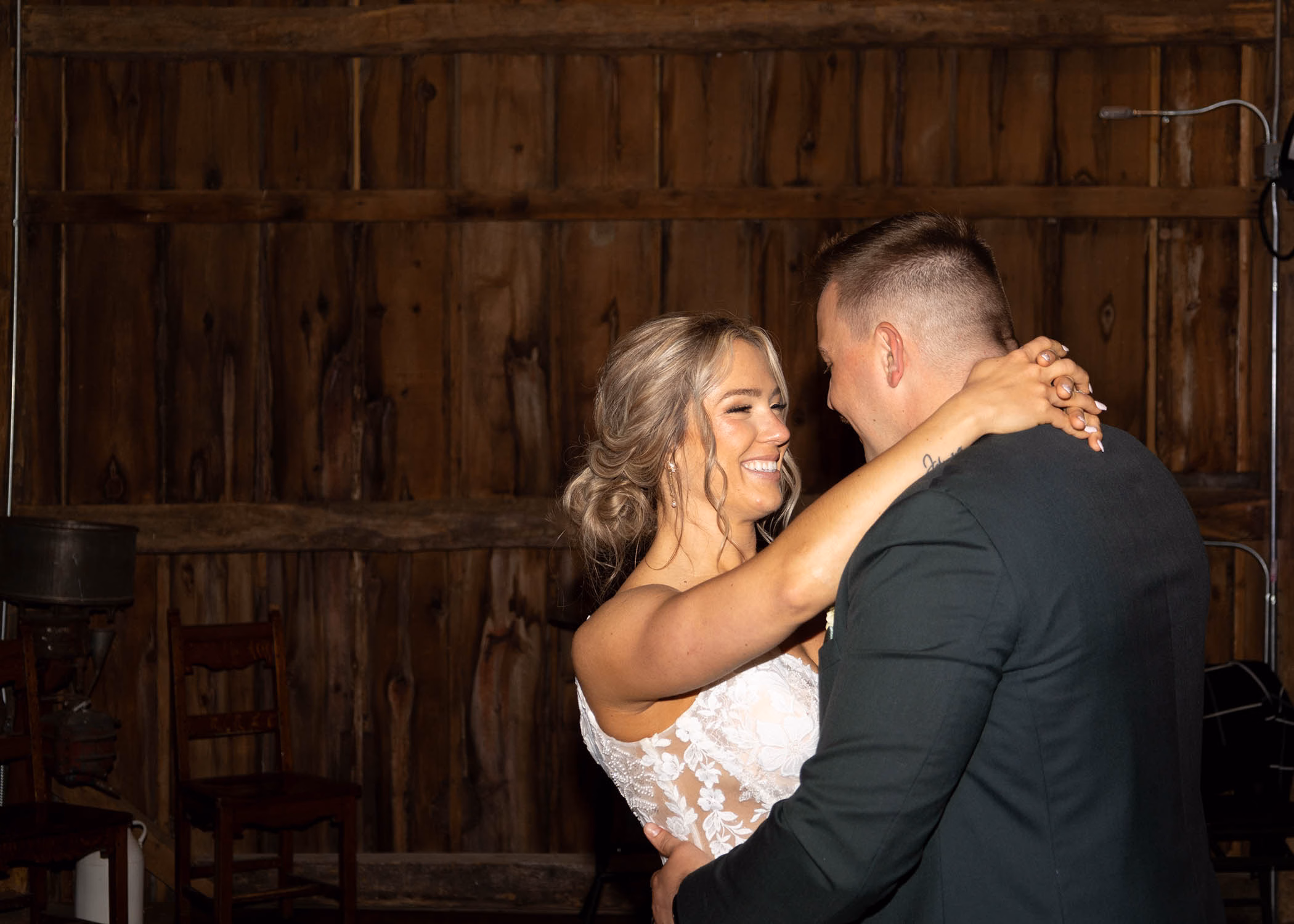 A bride and groom sharing their romantic first dance inside a rustic wooden barn venue, captured by La Crosse, Wisconsin wedding photographer Captured by Nancy Christine Photography.