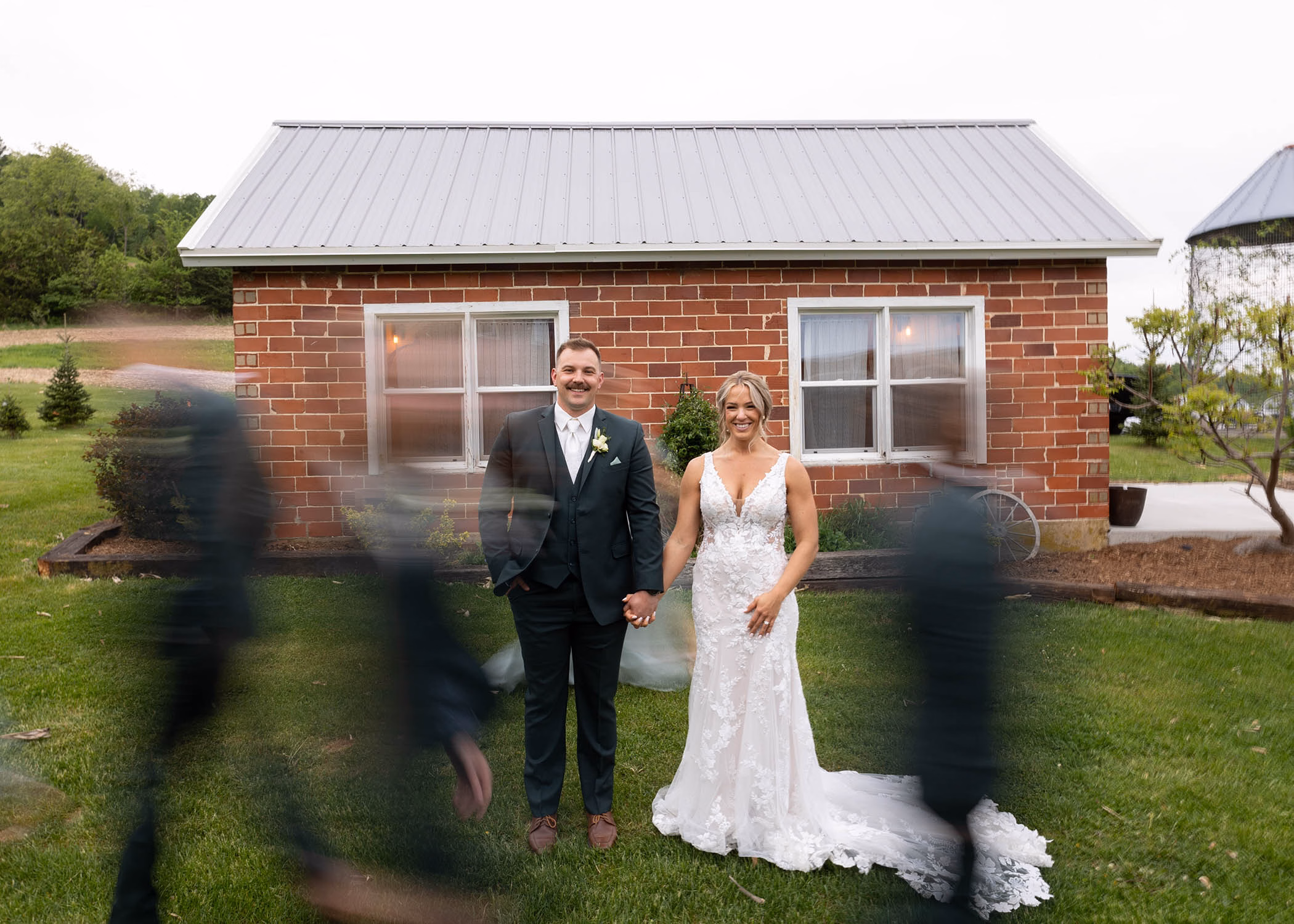 A creative wedding portrait of a bride and groom standing still while guests are blurred in motion around them, captured by La Crosse, Wisconsin wedding photographer Captured by Nancy Christine Photography.